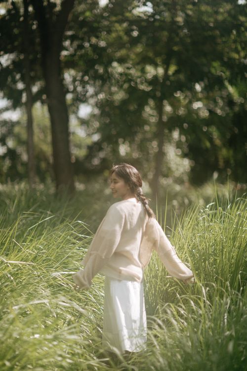 Free A woman wearing casual clothes stands in lush green grass on a sunny day outdoors. Stock Photo