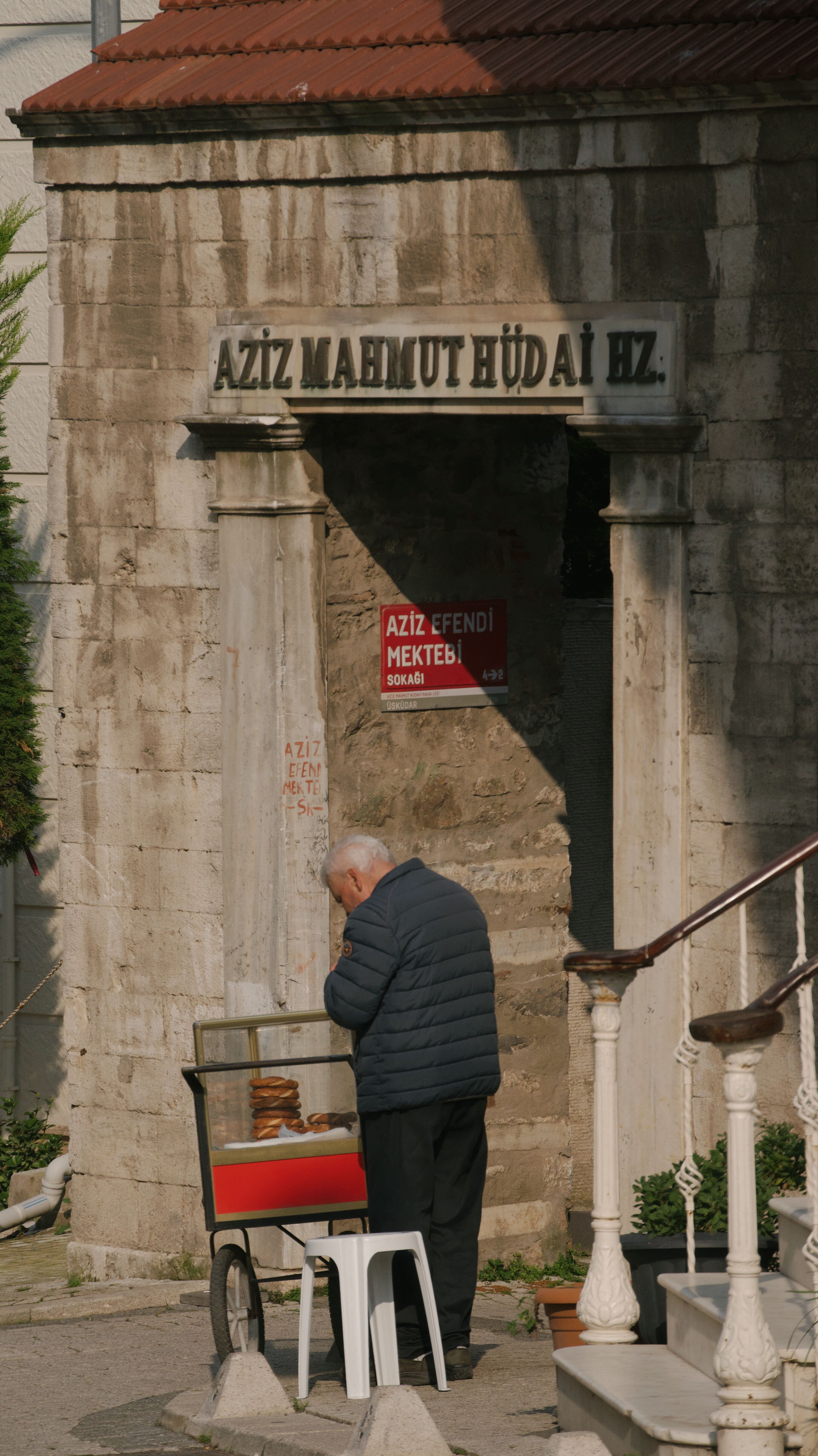 Elderly man selling simit beside Aziz Mahmud Hüdayi Türbesi in İstanbul, Türkiye.