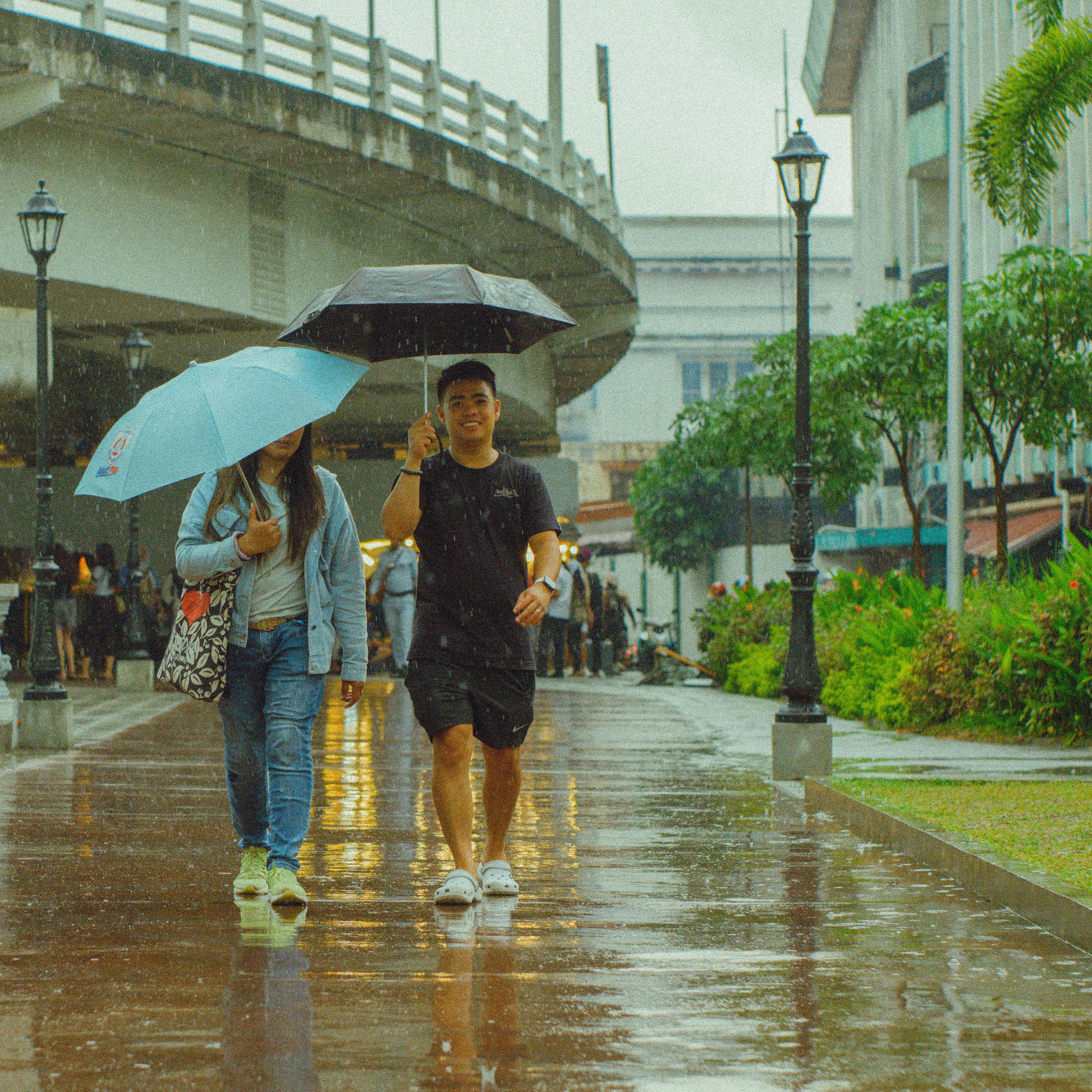A couple walks under umbrellas in a vibrant city during rain, embracing the urban atmosphere.
