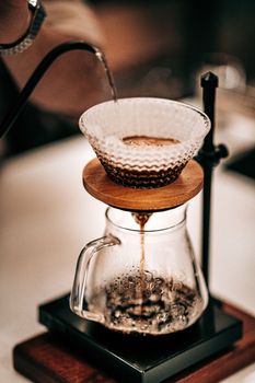 Close-up of a pour-over coffee setup with glass and wooden elements, creating a warm ambiance.