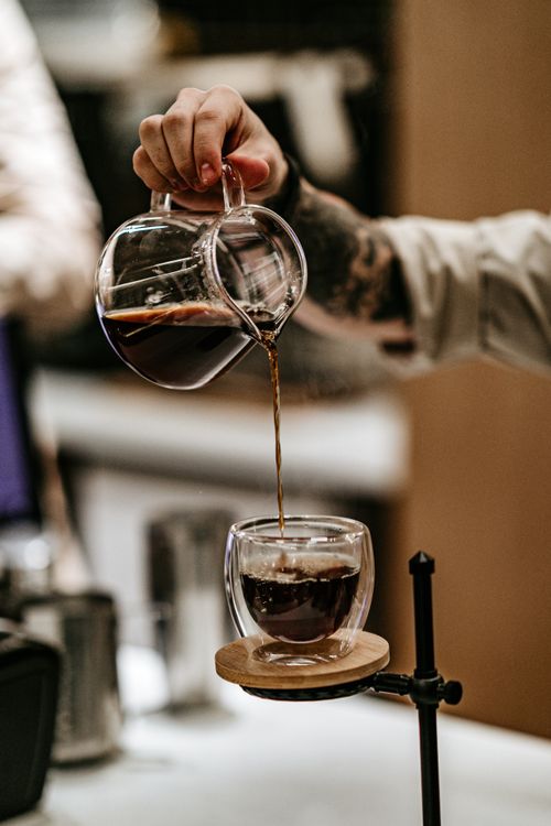 Free Close-up of a barista pouring freshly brewed coffee in a modern cafe setting. Stock Photo