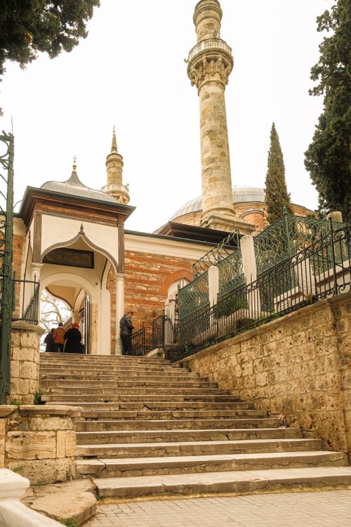 Free A stone staircase leads to a historic mosque with towering minaret and archway entrance. Stock Photo