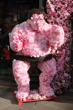 Creative sumo wrestler sculpture made of sakura blossoms displayed outdoors in London.