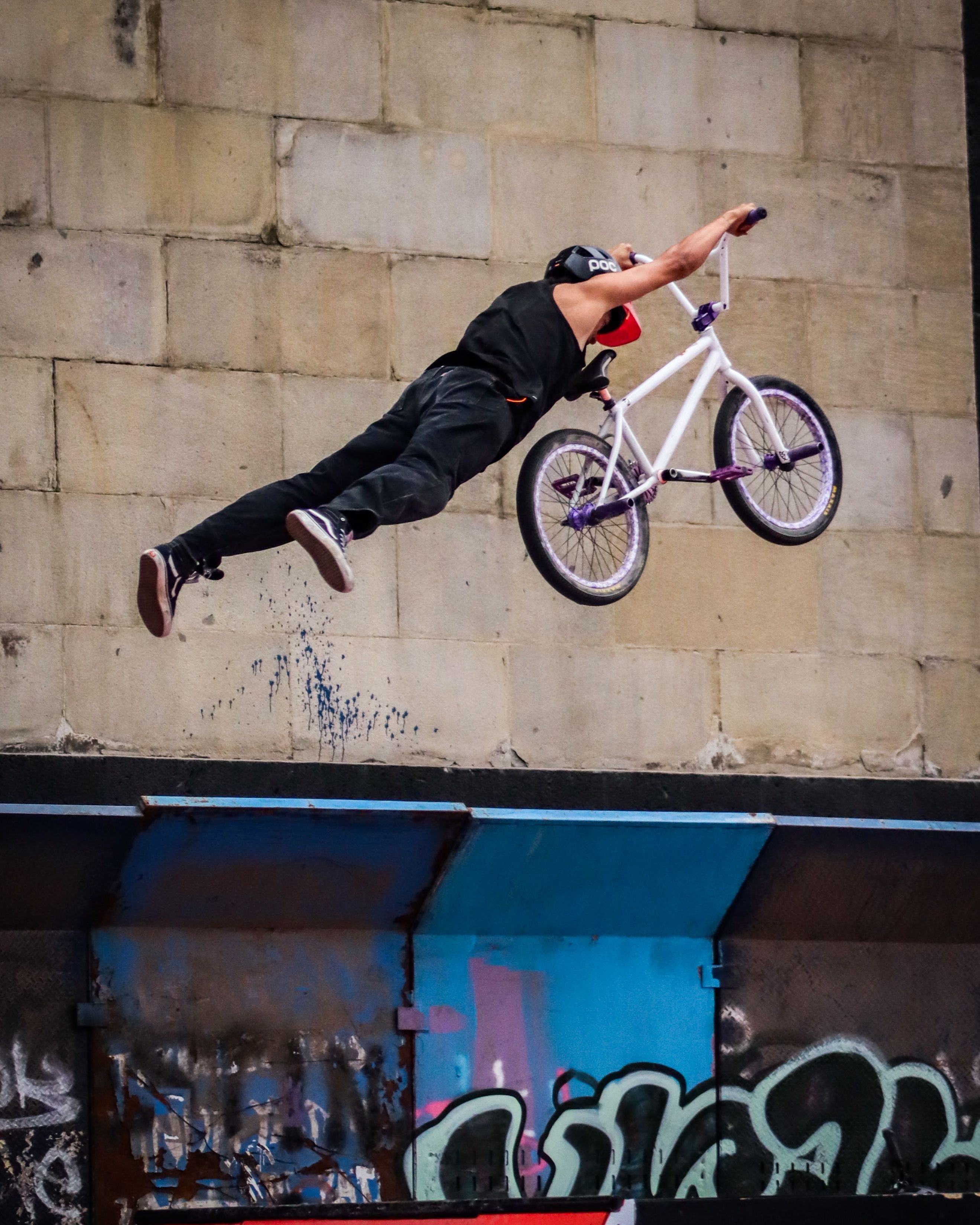 A daring BMX trick captured mid-air at an urban skateboard park with graffiti.