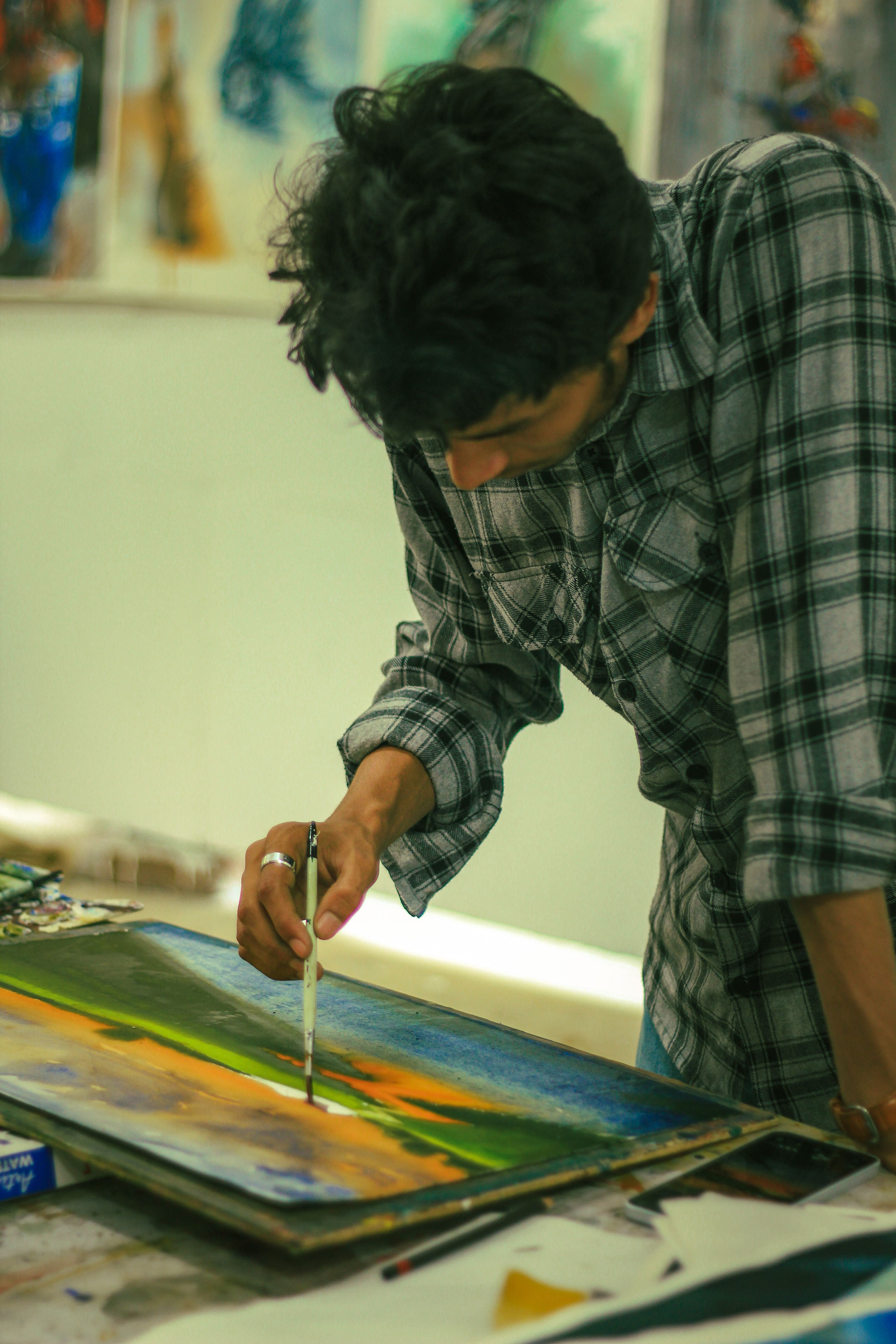 An artist skillfully paints a vibrant landscape in a Dhaka, Bangladesh studio.
