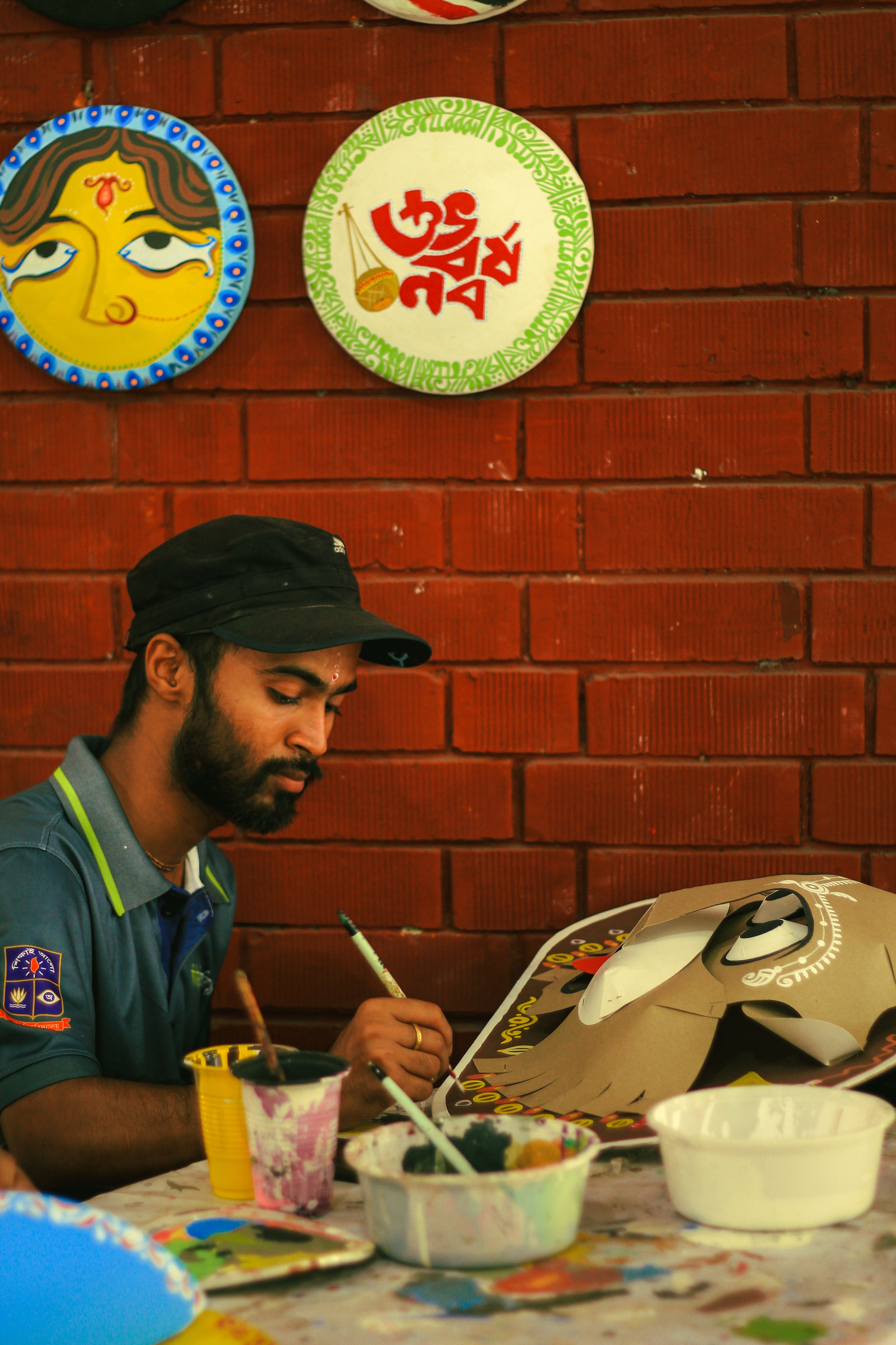 A young artist paints traditional masks in Dhaka's Faculty of Fine Art, featuring colorful designs and creative expression.