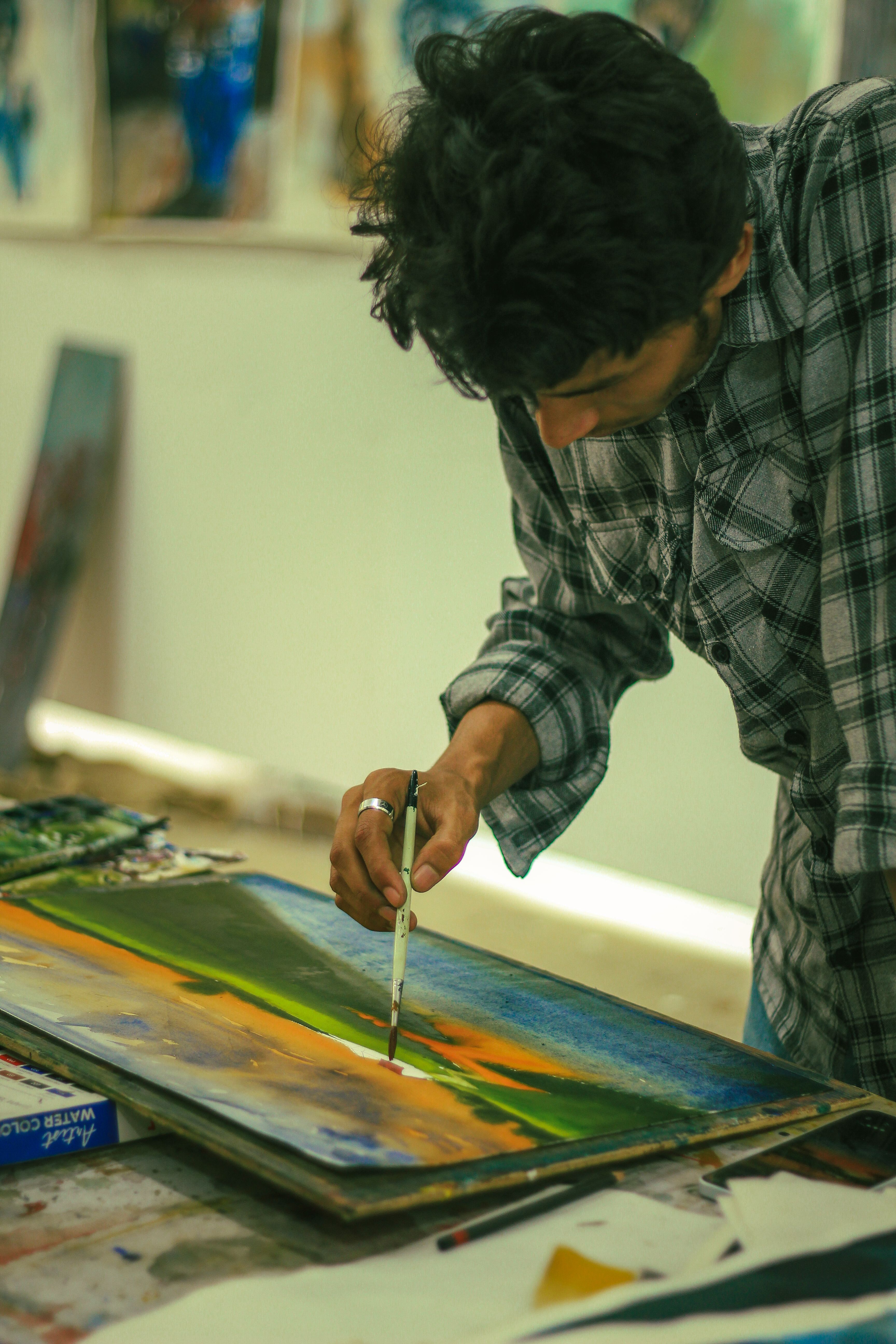 A focused artist paints a landscape in a studio environment in Dhaka, Bangladesh.