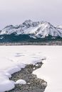 冬日晴朗的天空下，宁静的雪景、山脉与溪流相映成趣