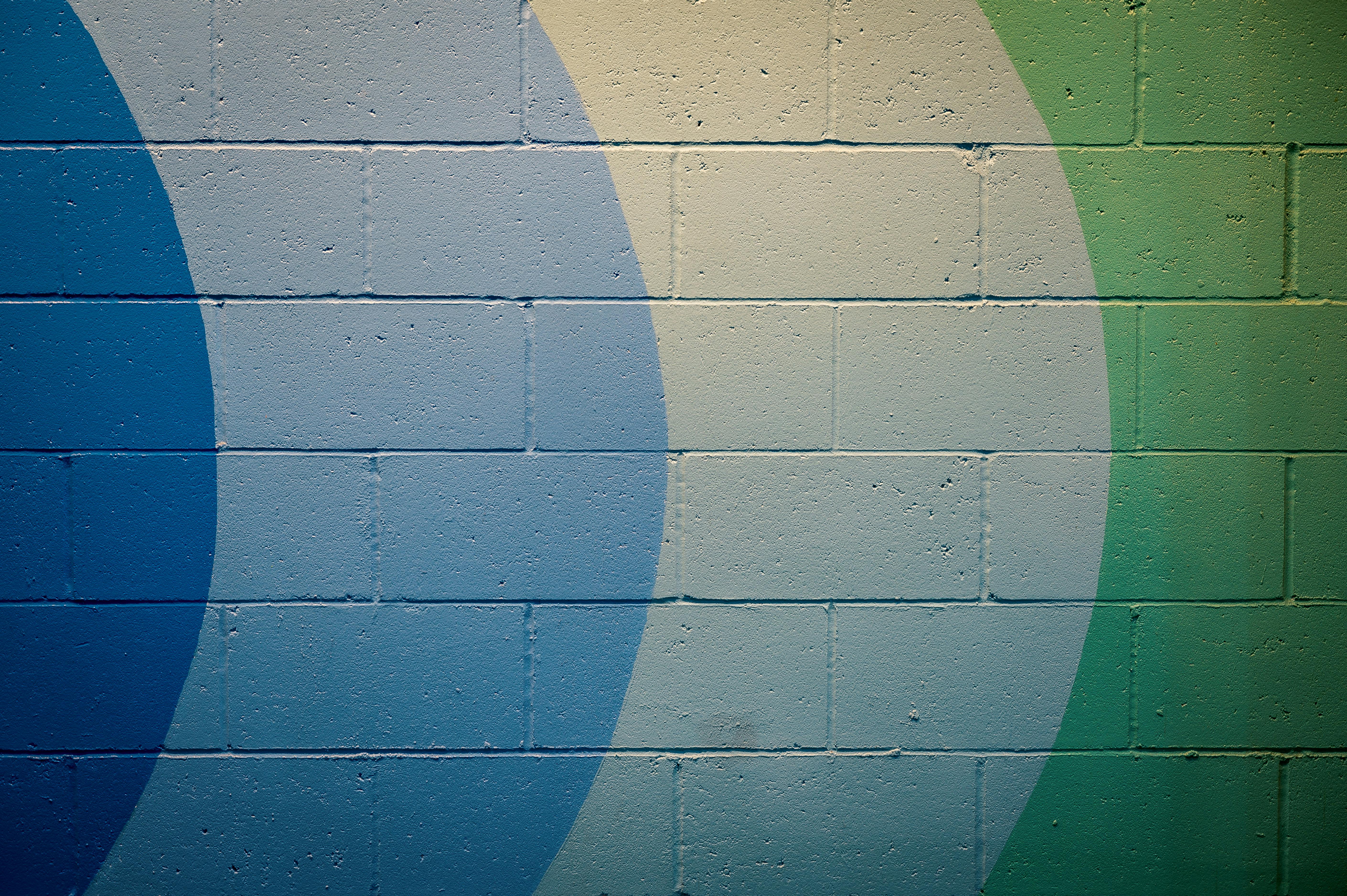 A vivid abstract mural with blue and green geometric patterns on a cement wall.