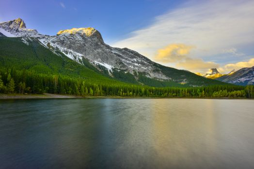 Dramatic sunrise over Kananaskis mountains and lake in Alberta, Canada, showcasing nature's beauty and tranquility.