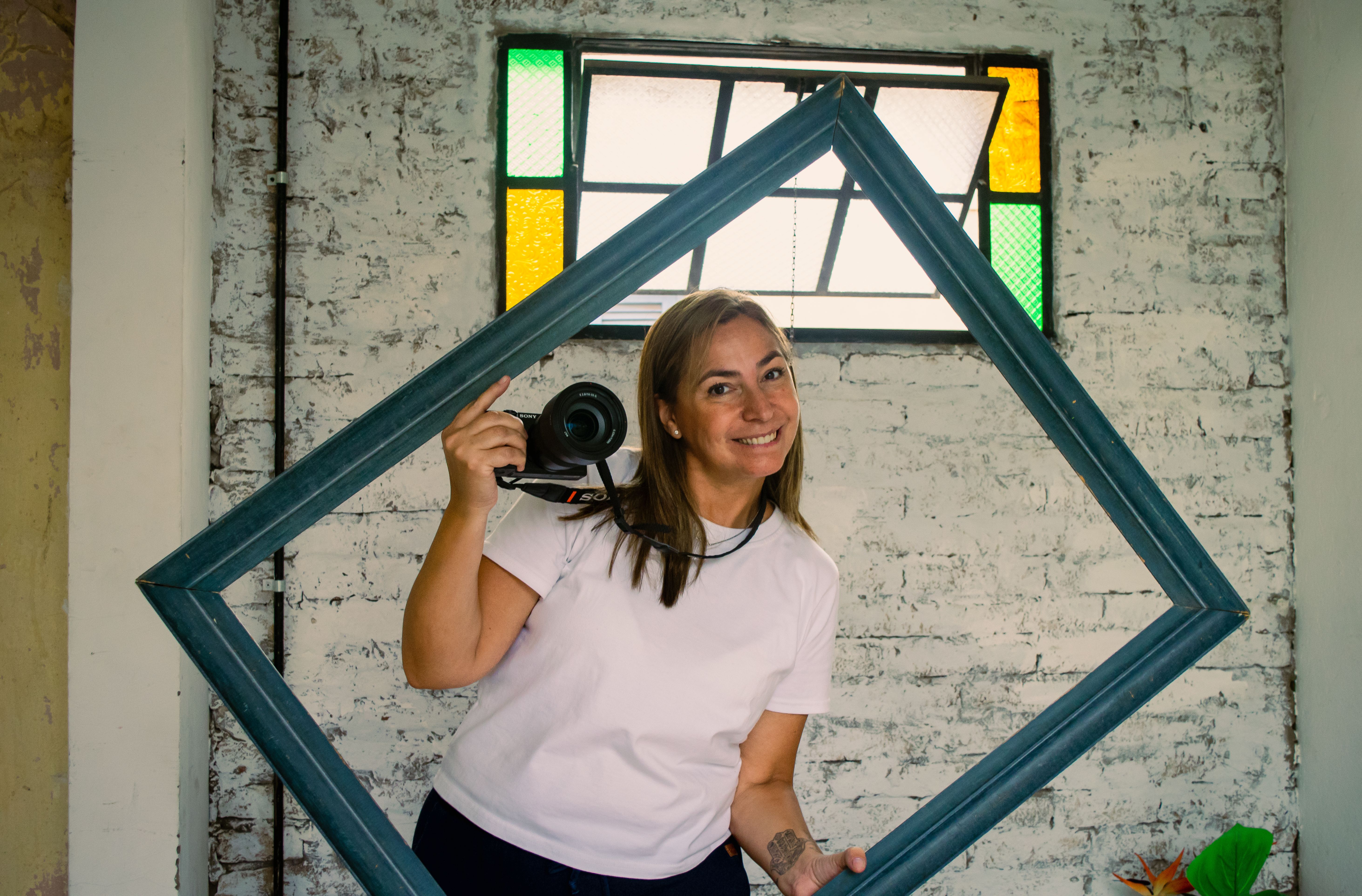 Woman Posing with Frame and Camera Indoors · Free Stock Photo