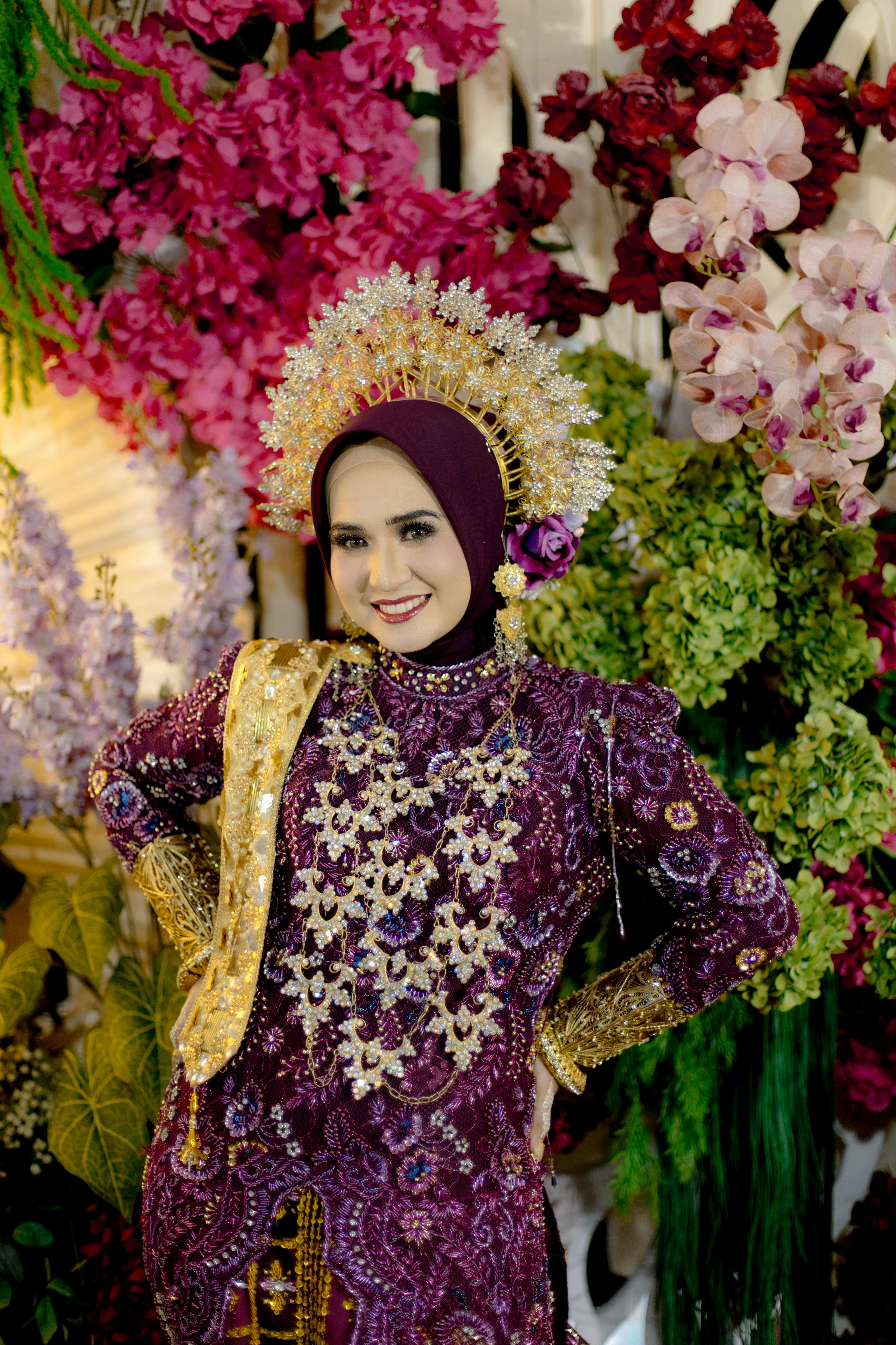 A stunning bride in ornate traditional dress surrounded by vibrant flowers.