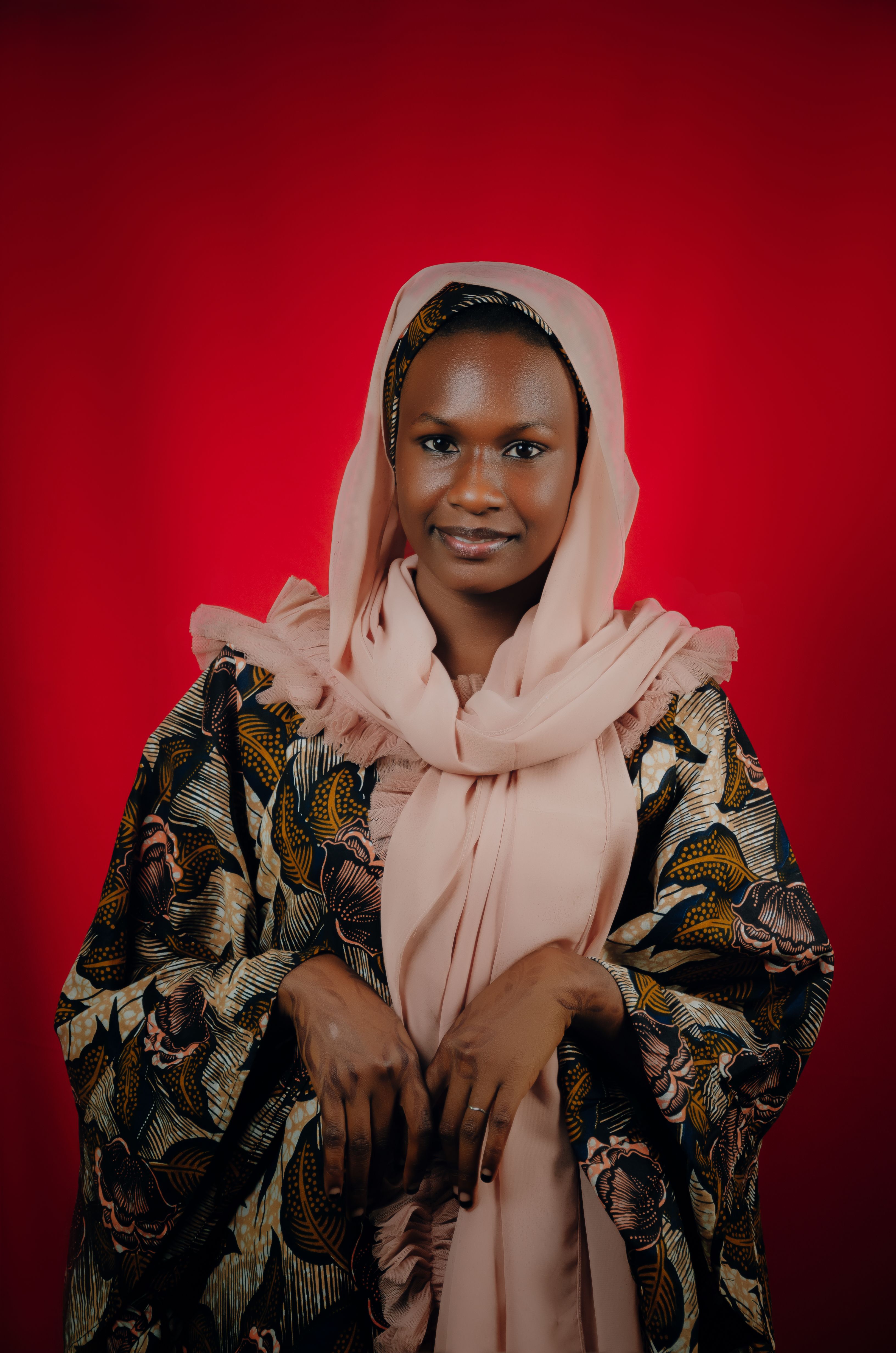 Captivating portrait of a woman in traditional African attire against a vibrant red background.