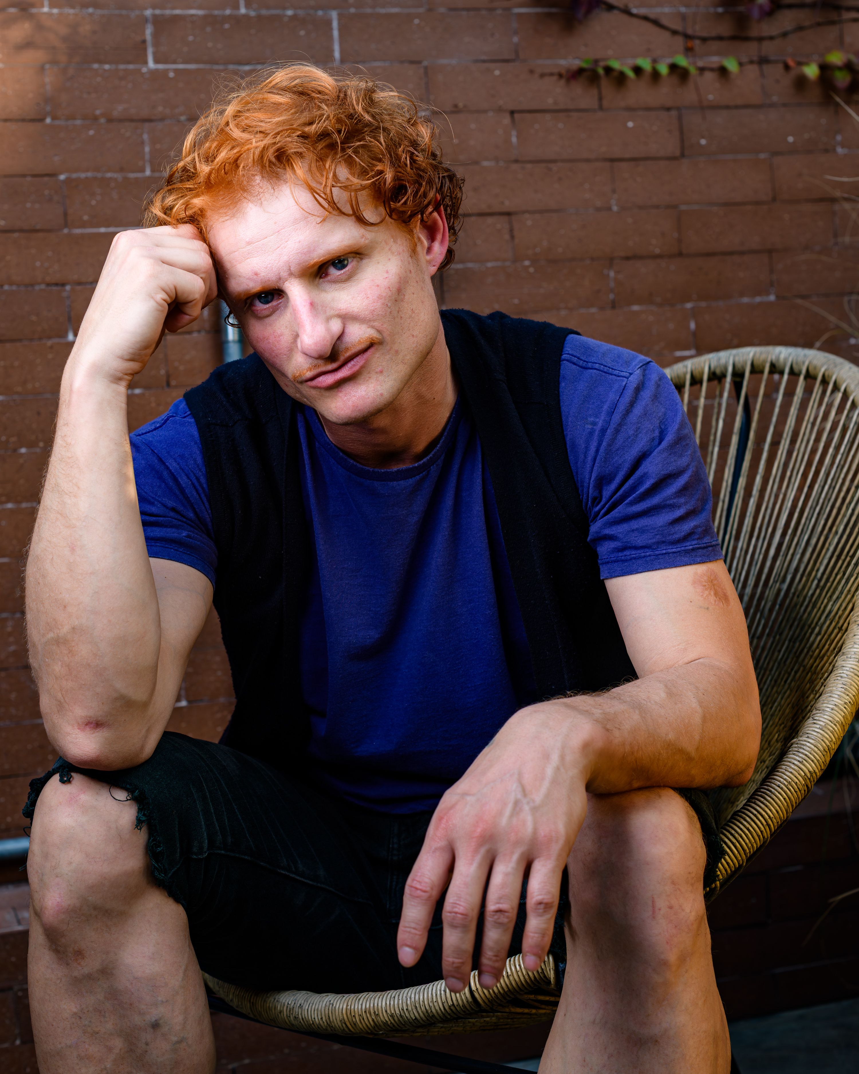 A man in casual attire sits outdoors in São Paulo, Brazil, with a thoughtful expression.