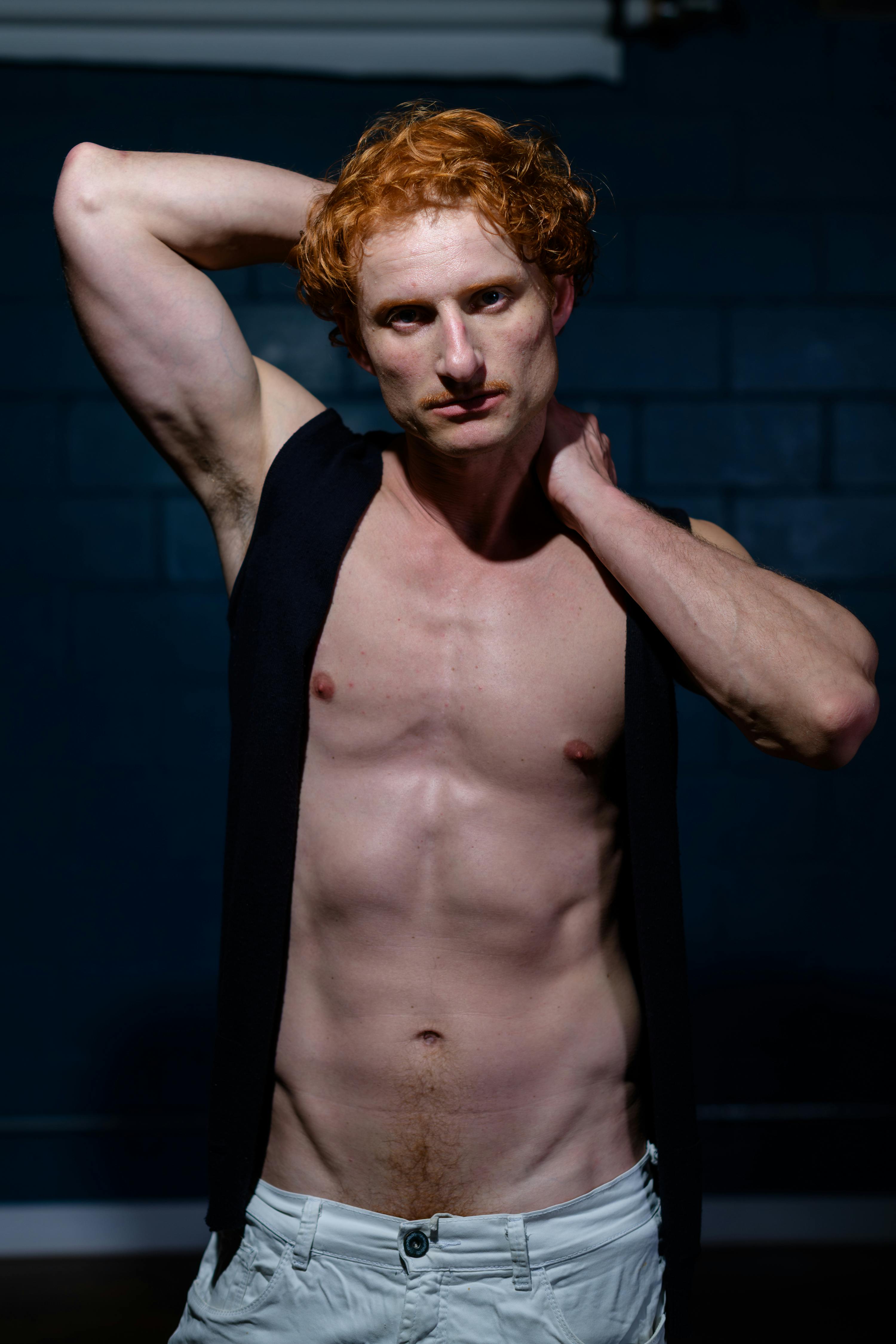 A striking portrait of a male model with ginger hair posing with confidence indoors.