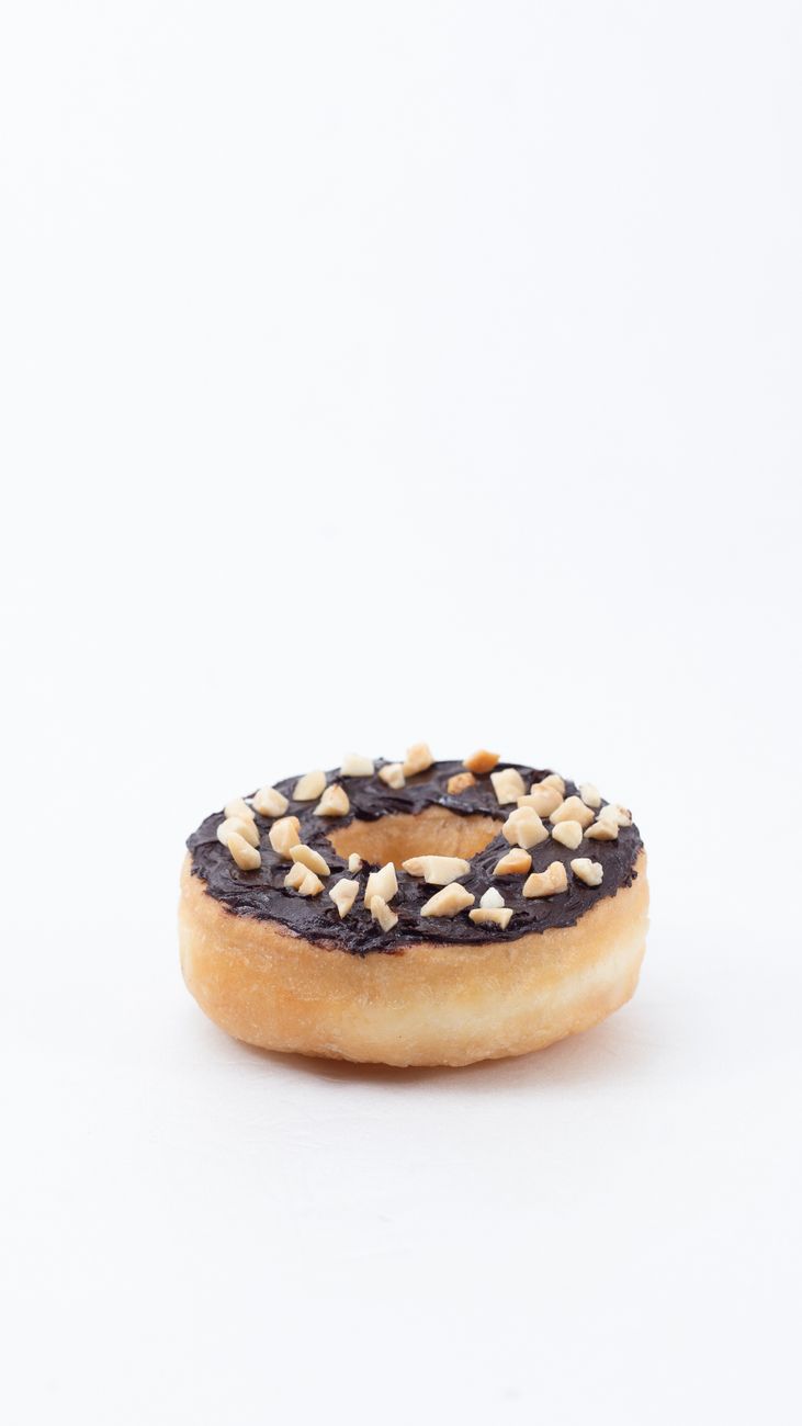 A sharp close-up of a chocolate-glazed donut with crunchy chopped nuts