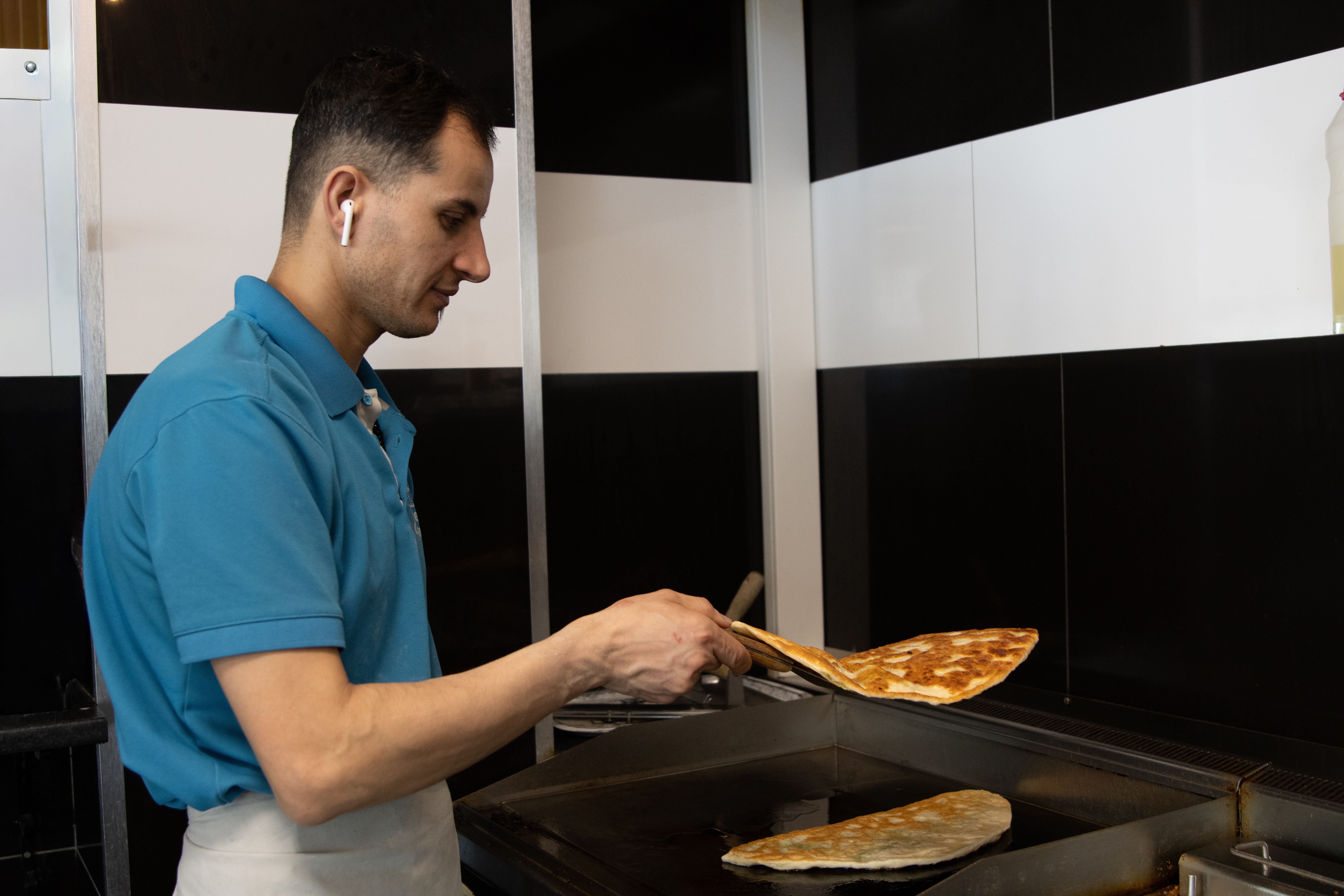 A chef wearing a blue shirt cooks a crepe on a griddle in an industrial kitchen in Jönköping, Sweden