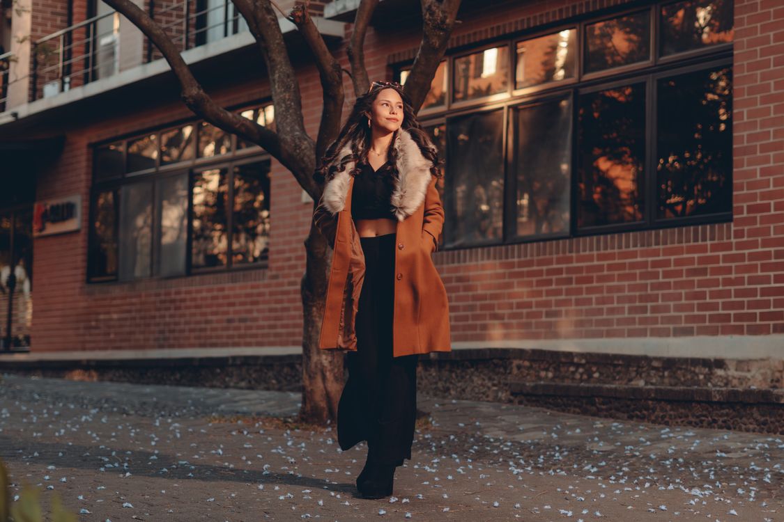 Stylish Woman Walking in Urban Setting at Sunset · Free Stock Photo