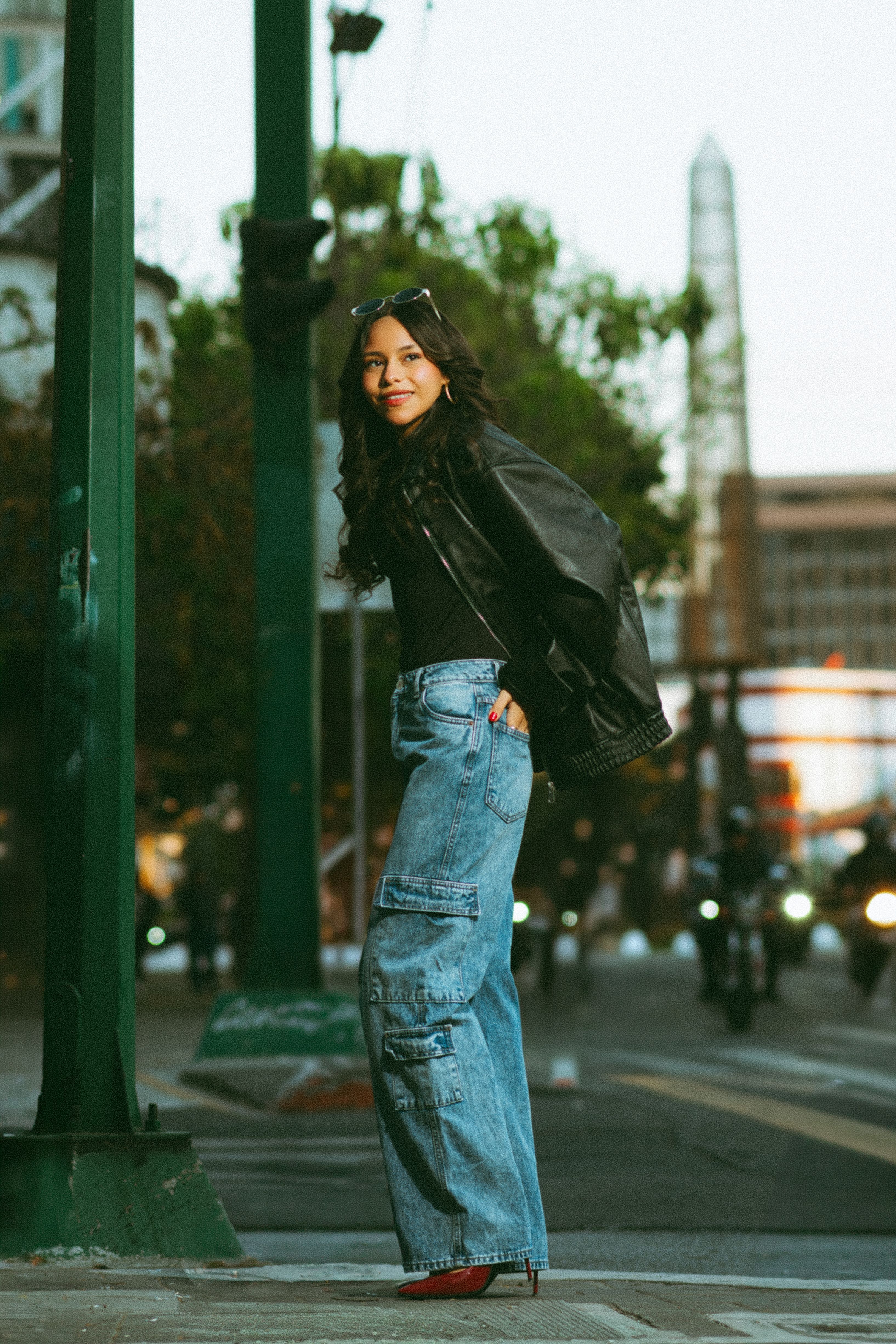 Young woman in fashionable streetwear posing outdoors in city.