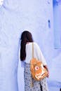 在摩洛哥谢夫沙万的蓝墙上，一位年轻女子背着背包倚靠着