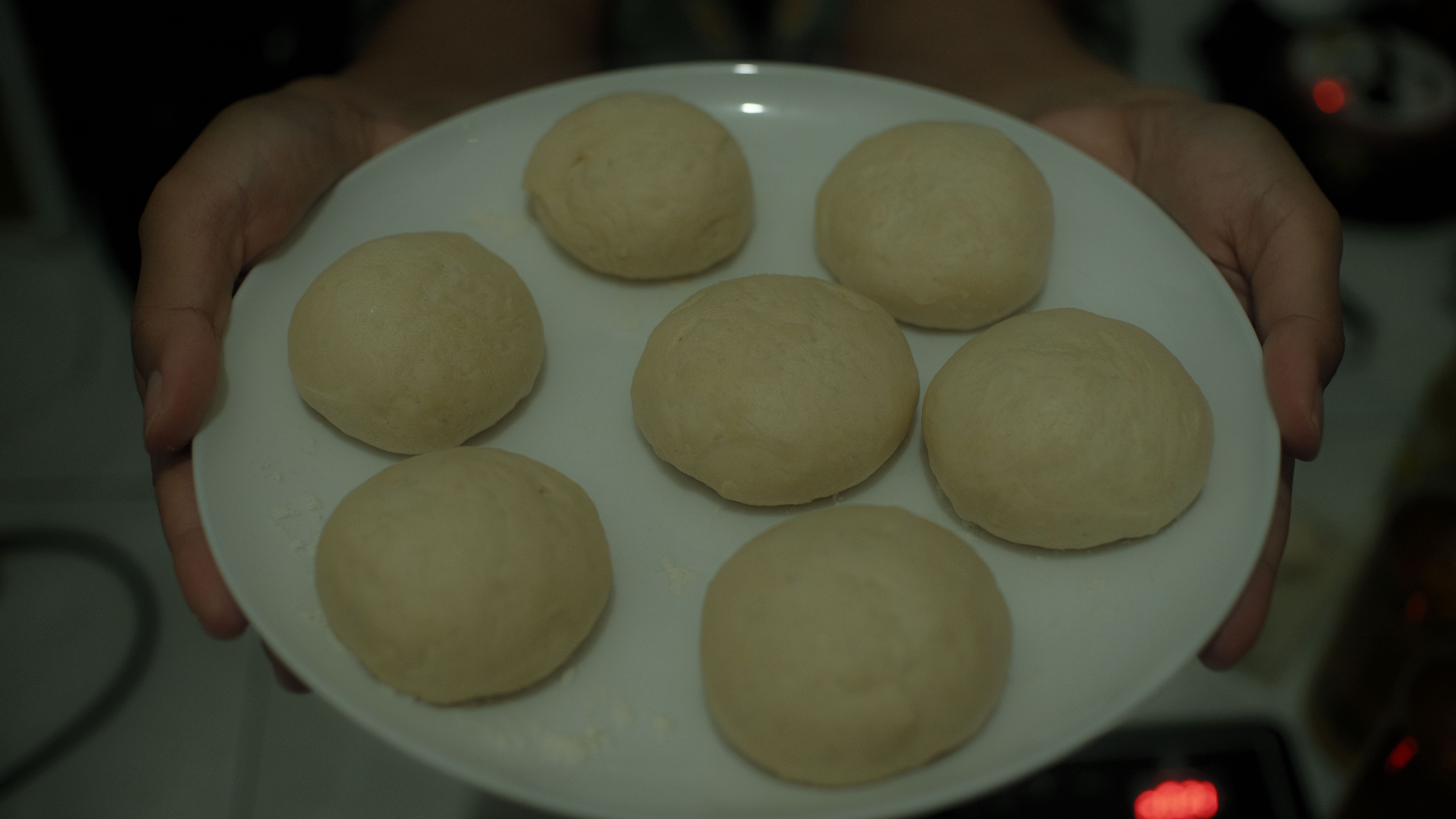 Close-up view of fresh bread dough balls on a plate indoors.