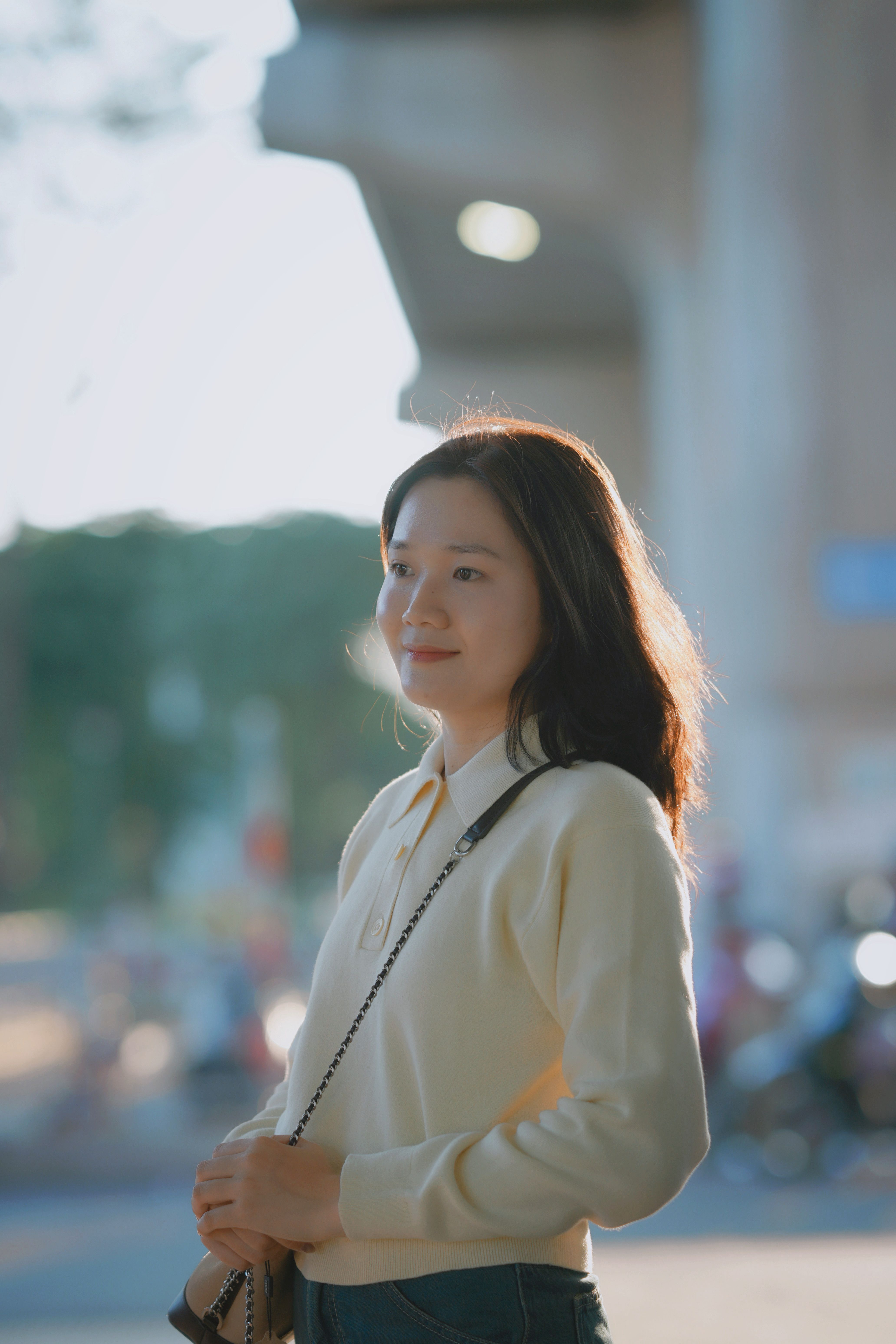Portrait of a young woman smiling in a sunny outdoor setting, capturing a serene moment.