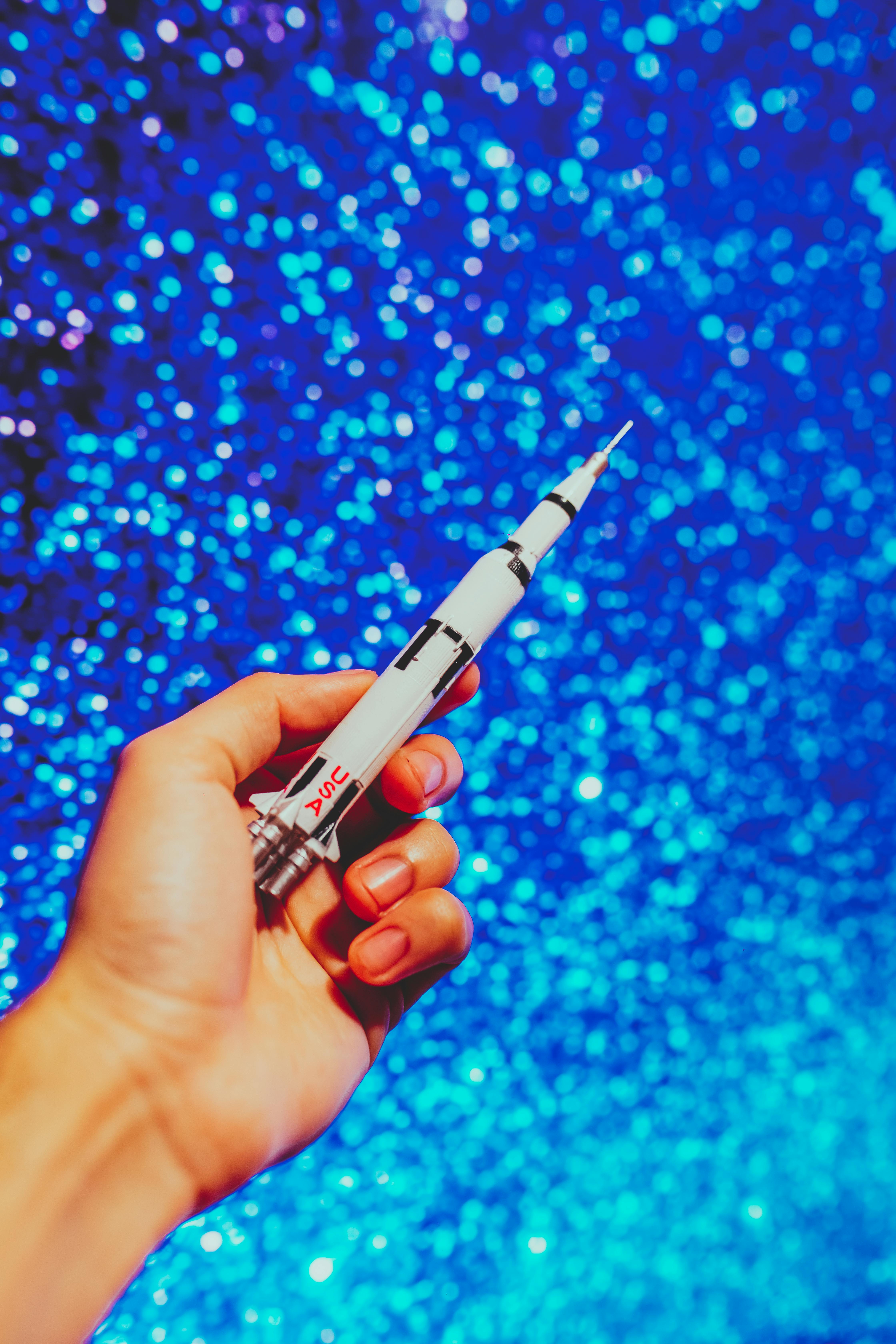 person holding a miniature rocketship click pen