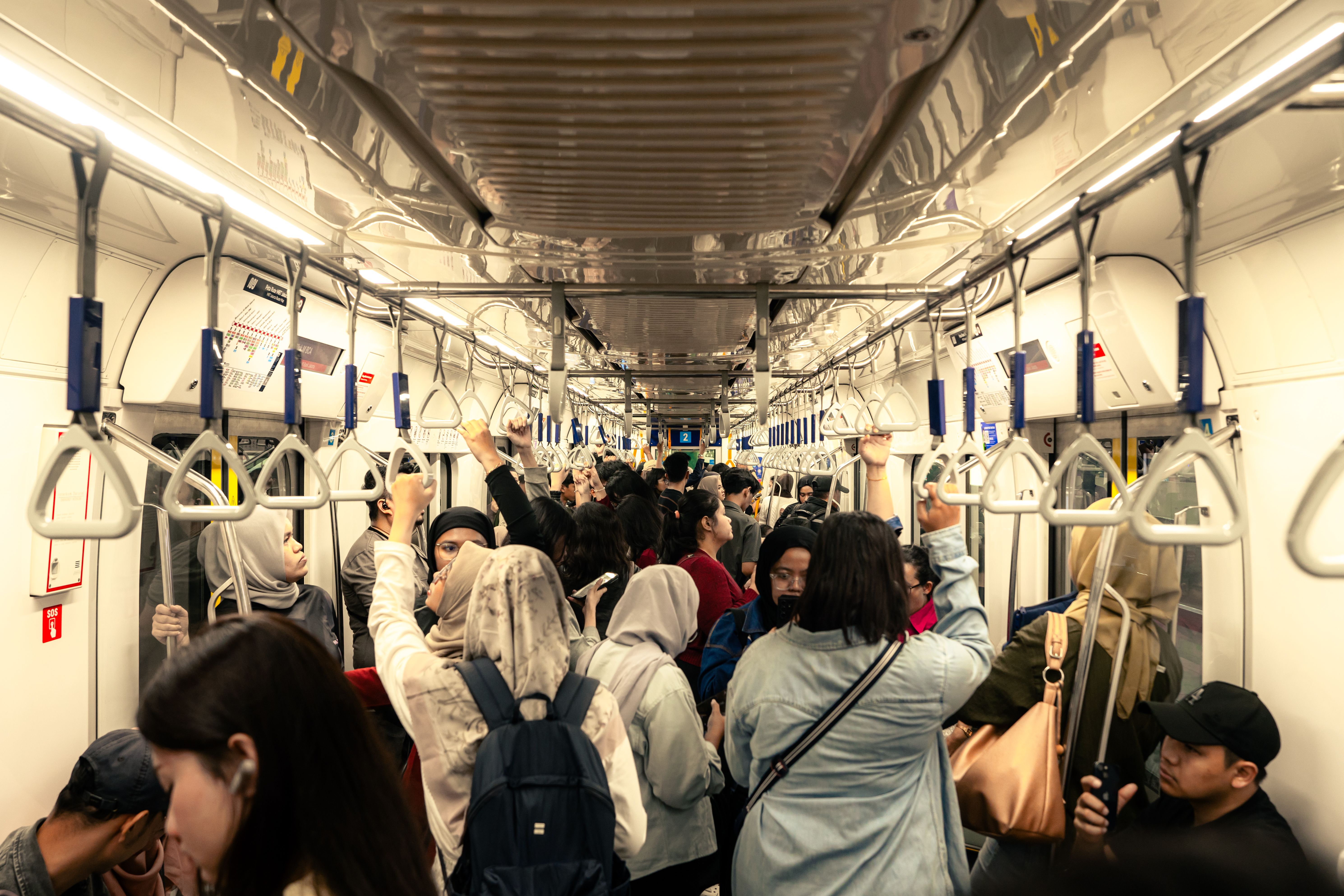 Crowded subway scene in Jakarta, Indonesia, depicting a bustling commuter train filled with diverse passengers.