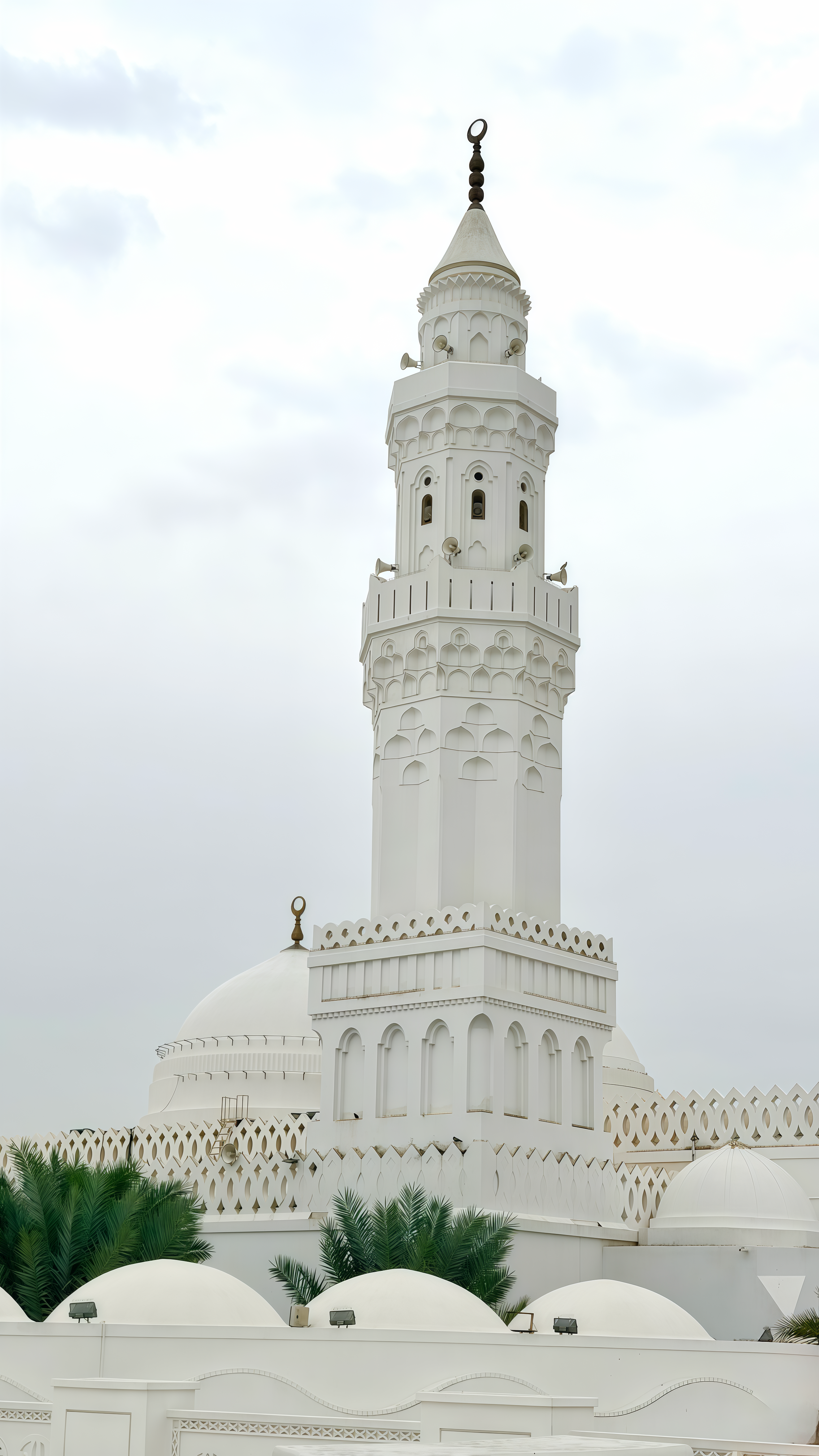 Majestic view of Quba Mosque with its iconic white minaret and dome under a cloudy sky in Madinah.