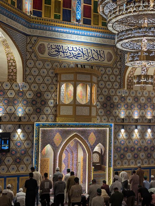 Free A group of adults praying in a mosque with intricate decorative patterns and Arabic calligraphy. Stock Photo