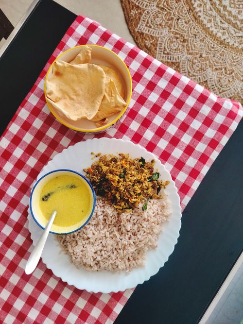 Free A traditional Indian meal featuring rice, curry, and papadam on a red checkered cloth. Stock Photo