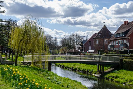 Peaceful spring scene with a bridge over a creek and historic buildings in Coesfeld, Germany.