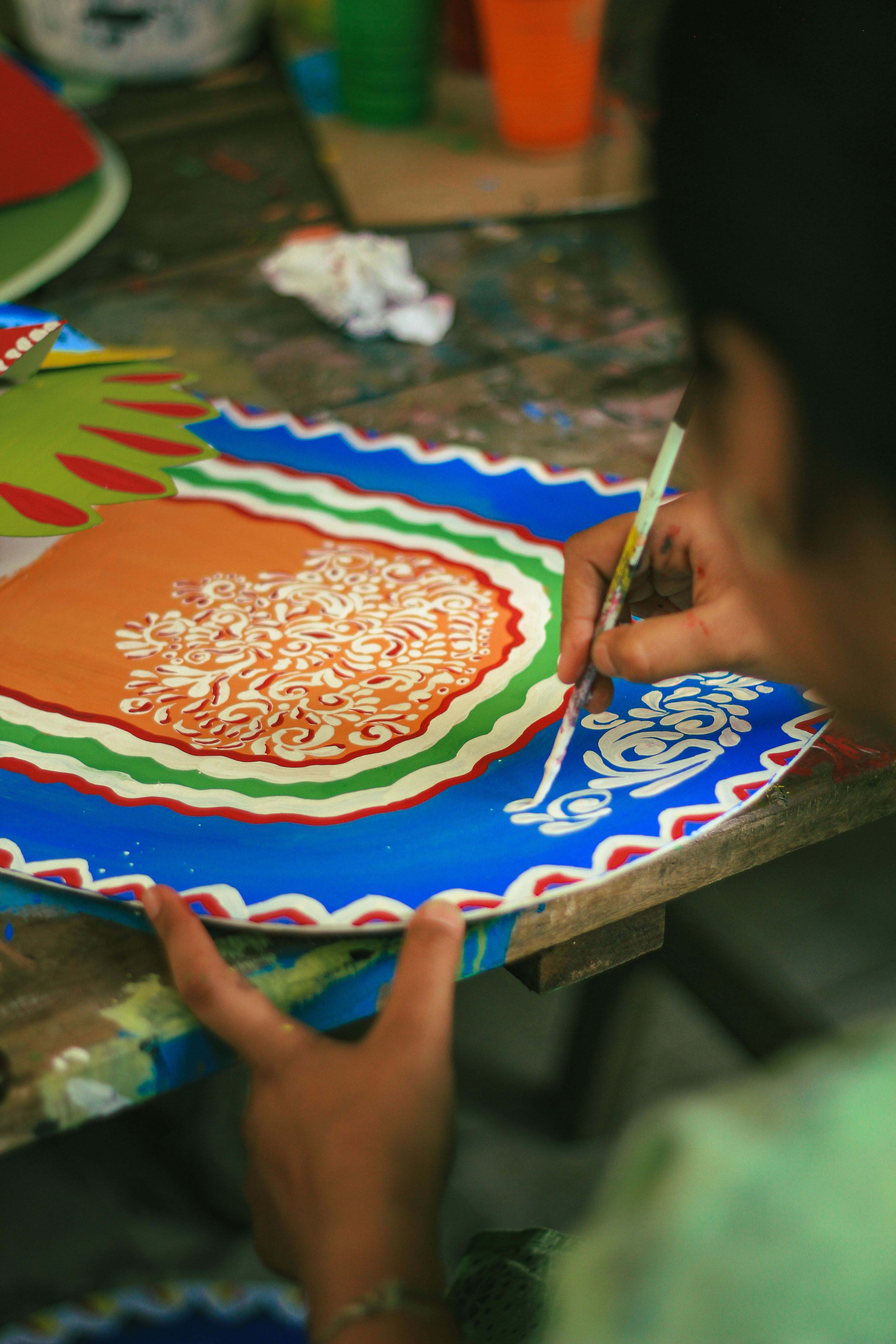 A person intricately painting a colorful traditional design in Dhaka, Bangladesh.