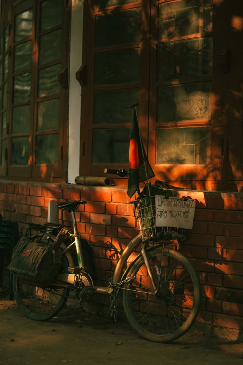 Free A vintage bicycle adorned with a Bangladeshi flag leans against a rustic brick wall in Dhaka, Bangladesh. Stock Photo