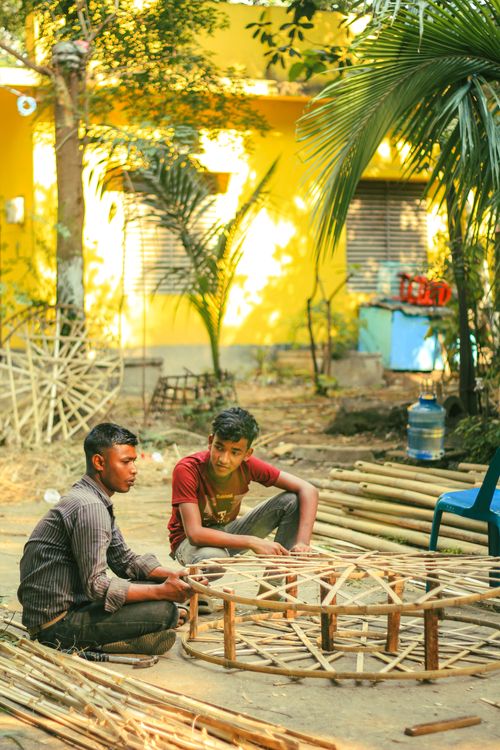 Free Two men building bamboo frames outside in Dhaka, Bangladesh on a sunny day. Stock Photo