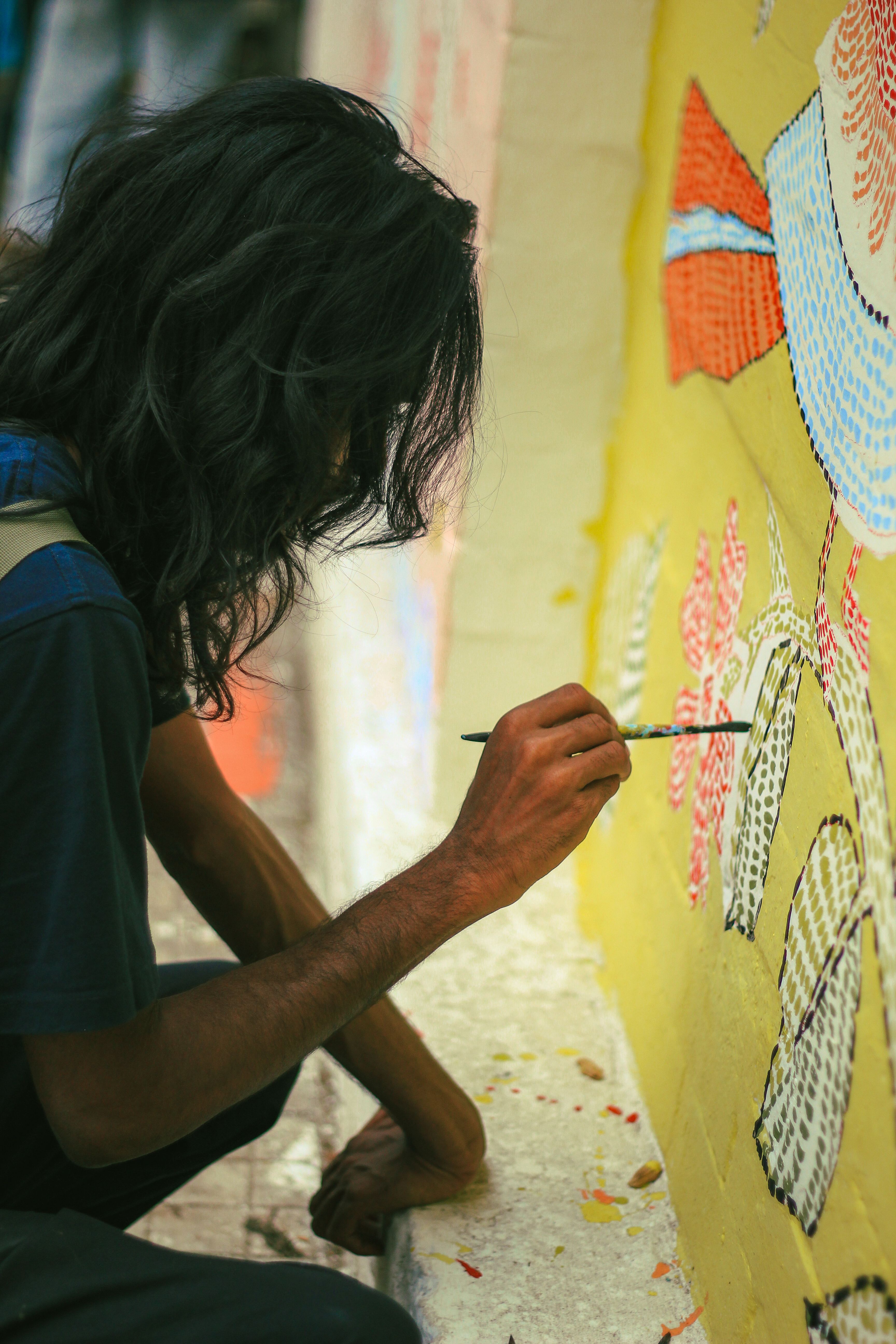 A street artist concentrates on painting a vibrant mural in Dhaka, highlighting cultural artistry.