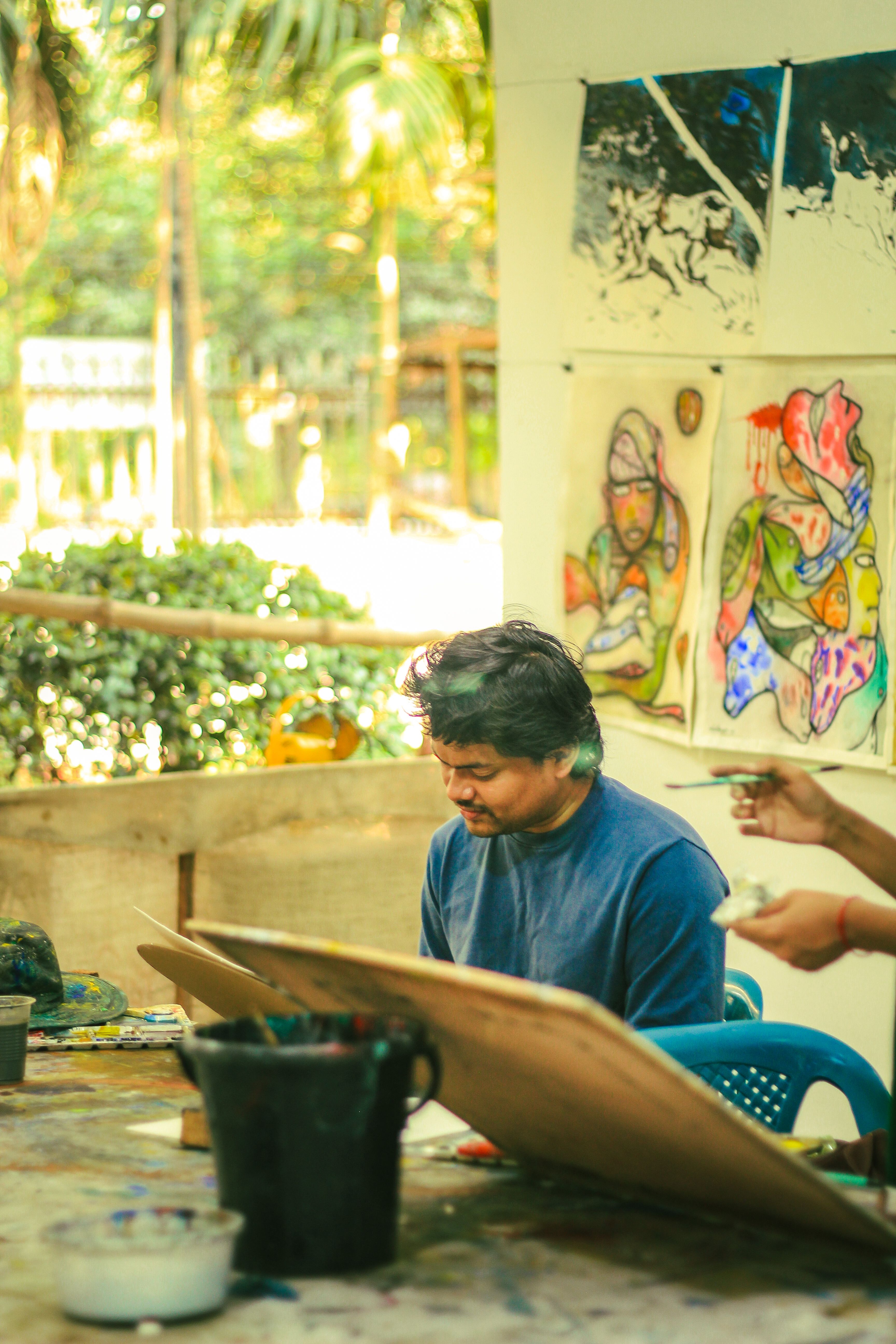 A male artist engaged in painting outdoors at the Faculty of Fine Art, Dhaka University.