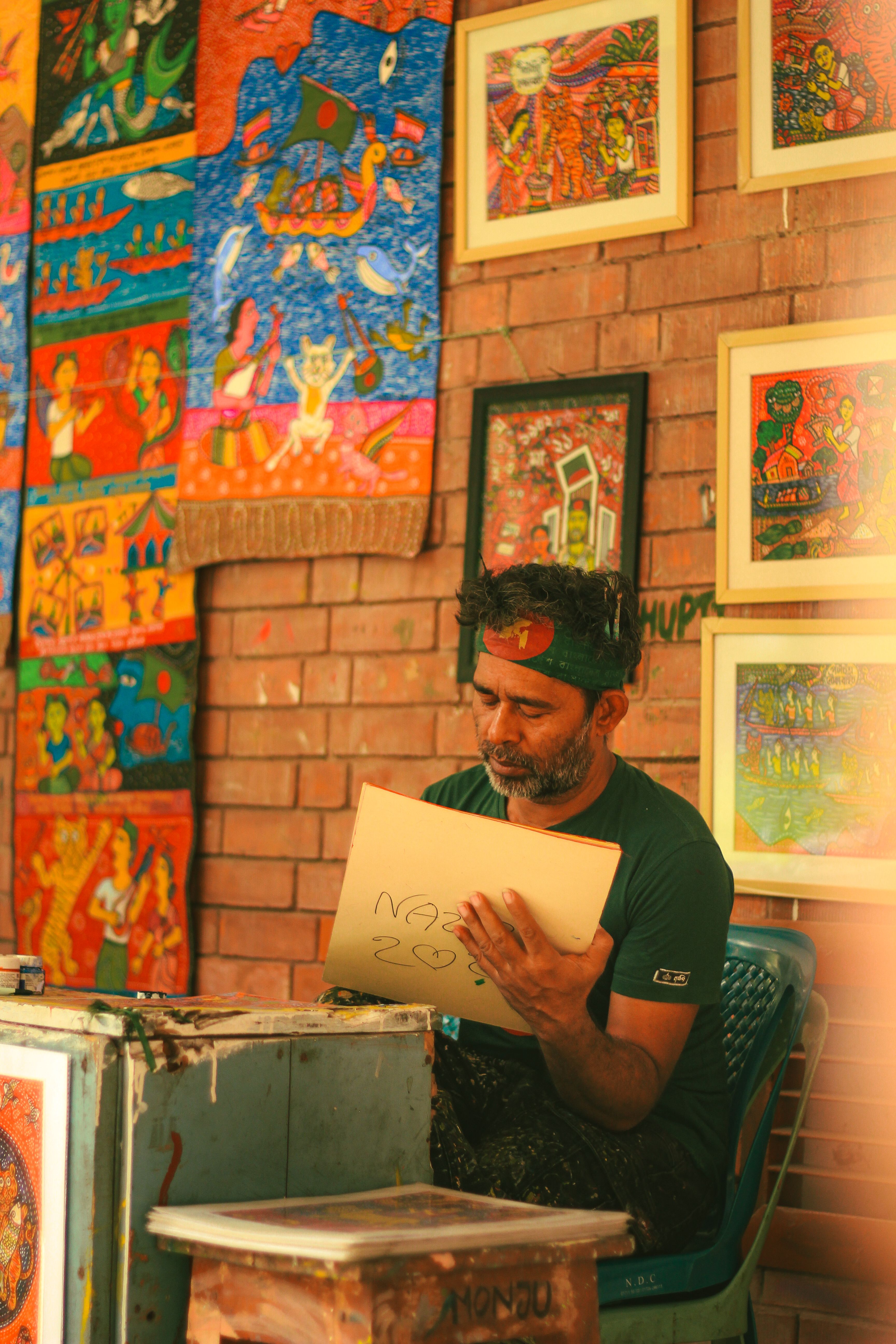 A male artist working on a colorful painting in a vibrant art studio in Dhaka, Bangladesh.