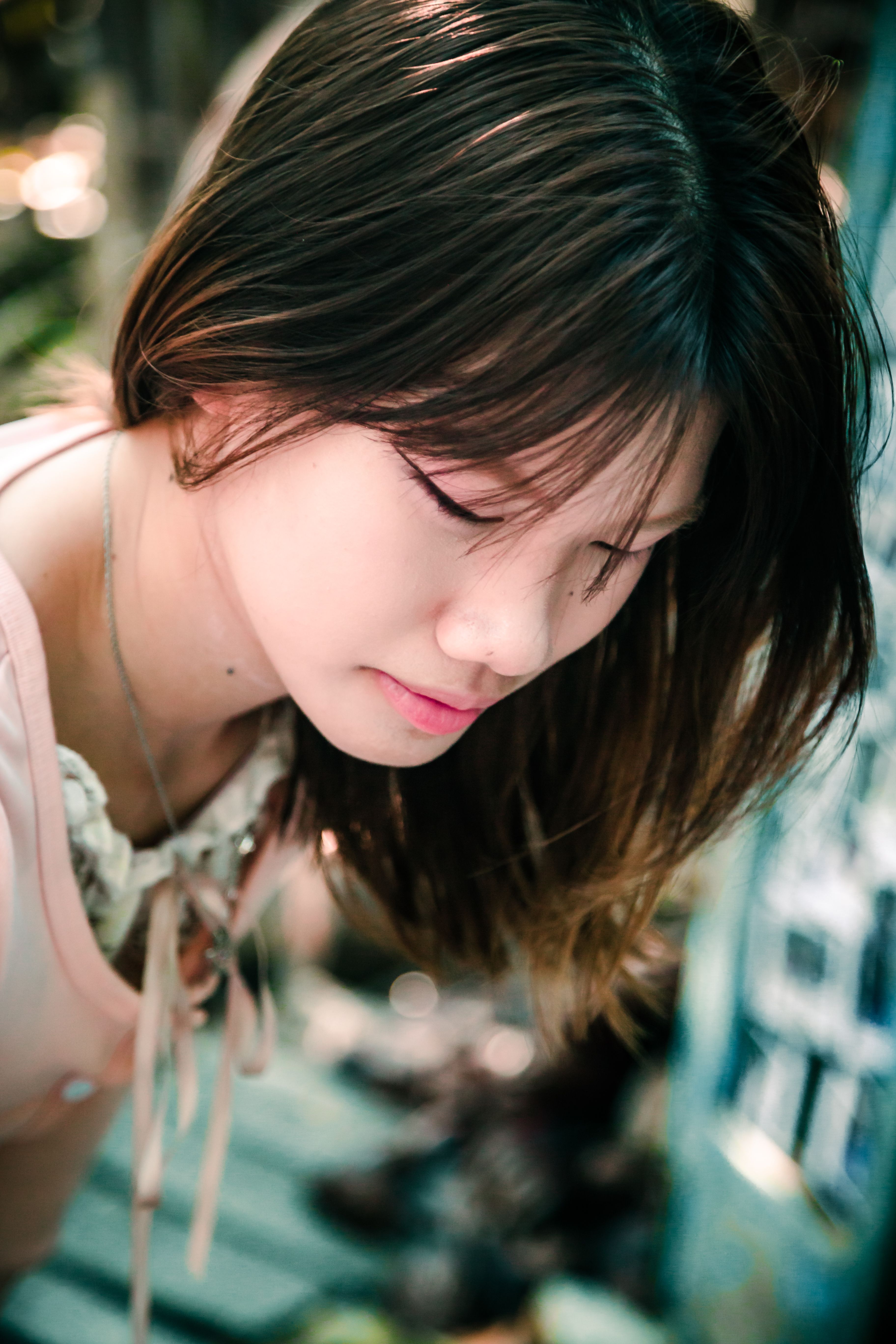 A young woman in a soft focus portrait with a thoughtful expression outdoors.