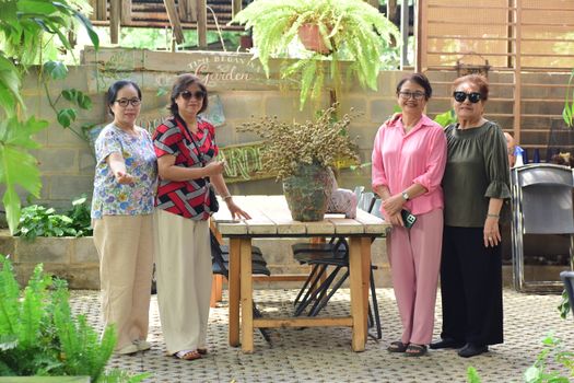 Four women posing together in a beautiful garden setting with lush greenery.