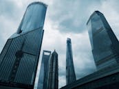 高耸的未来主义摩天大楼在阴云密布的天空下，展现出戏剧性的城市景观