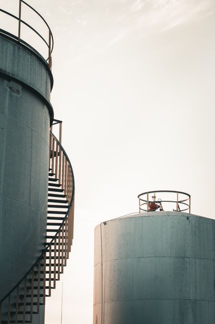 View of industrial silos with spiral staircase during sunrise, offering dramatic silhouette.