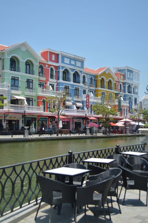 Free Vibrant colorful buildings line a riverside promenade with outdoor seating, exuding a European architectural charm. Stock Photo