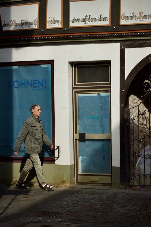 Free A man walks in an urban area past a closed shop with German text on the facade. Stock Photo