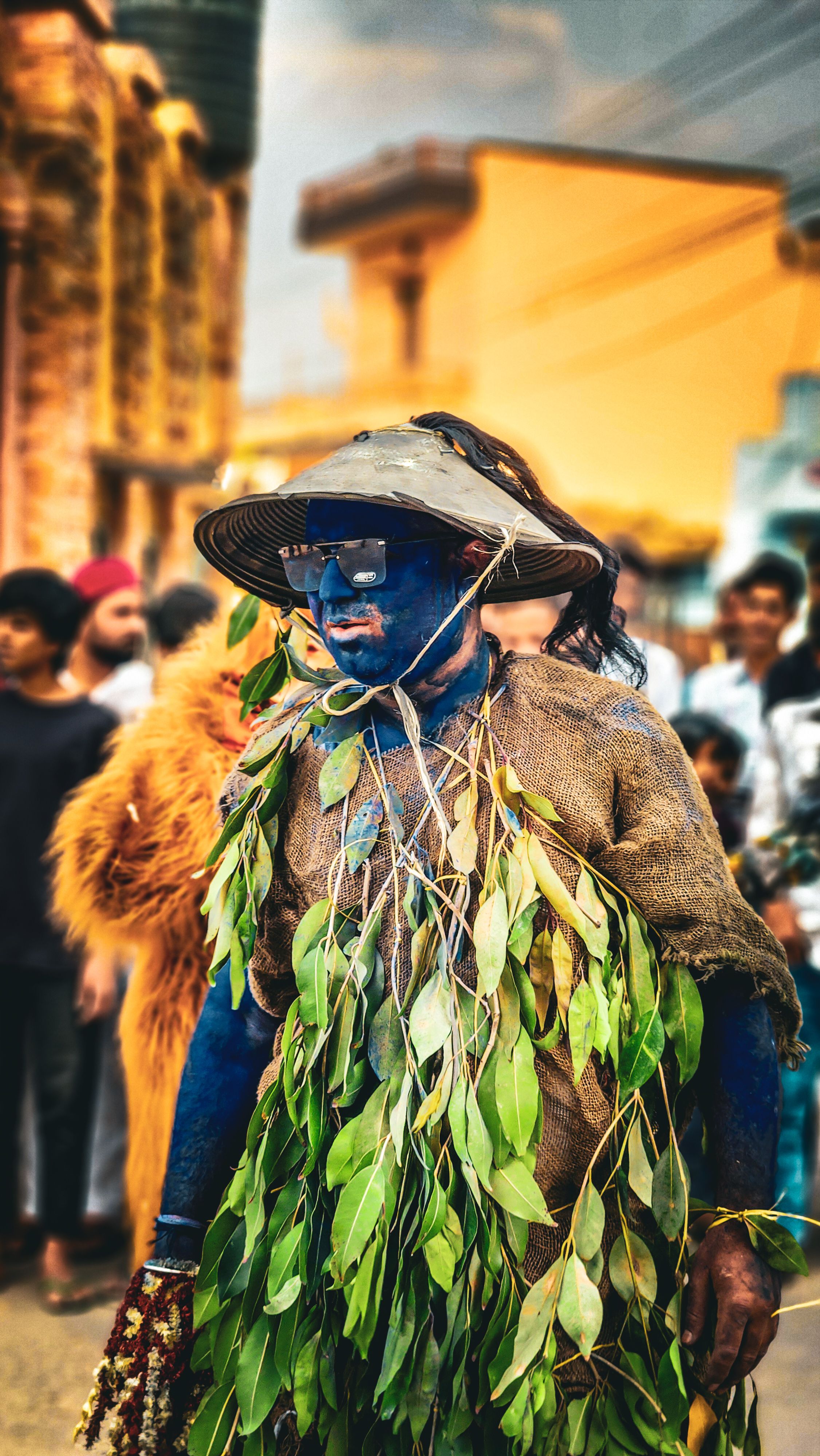 A vibrant festival performer painted blue, adorned with leaves participates in a traditional event in Didwana, Rajasthan.