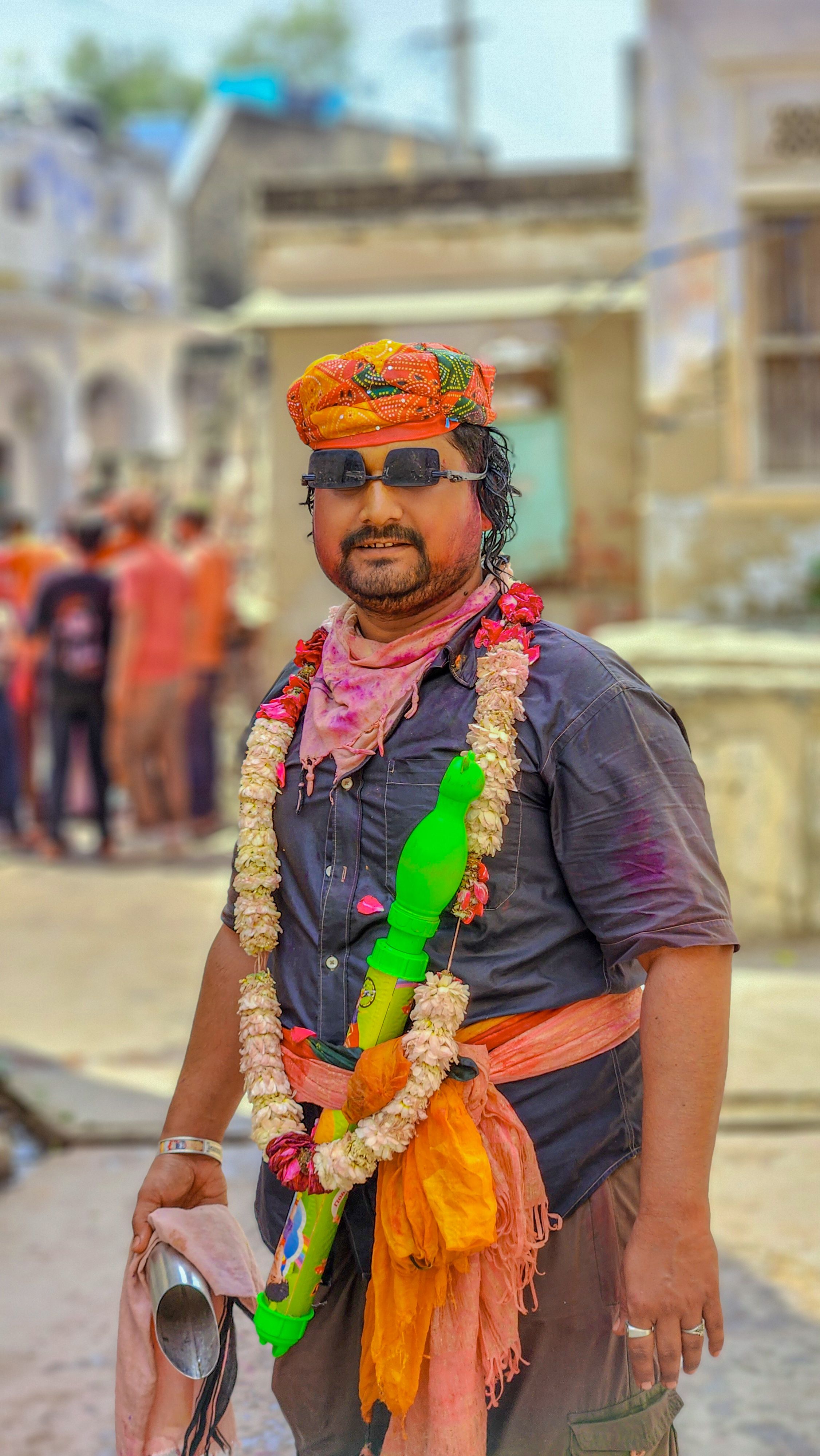 A man in festive attire celebrates Holi in a vibrant street scene from Didwana, Rajasthan, India.