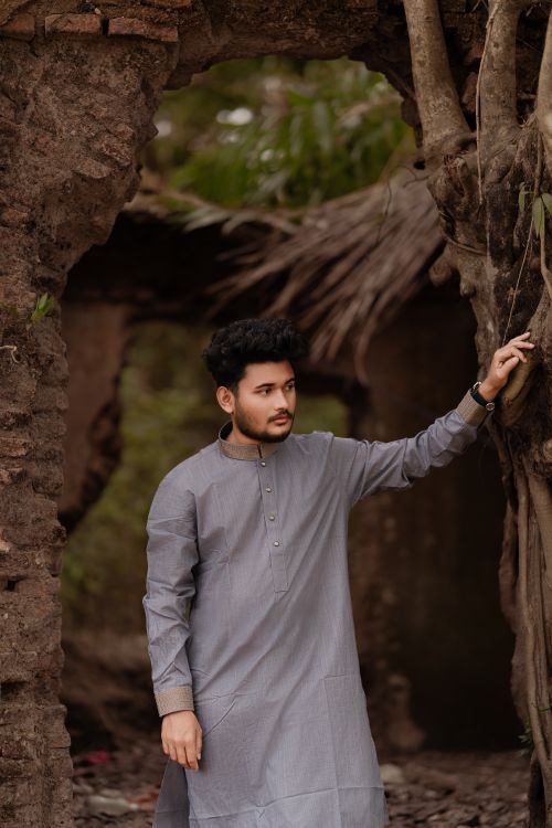 Free A young man in traditional Panjabi attire stands outdoors in rural Bangladesh. Stock Photo