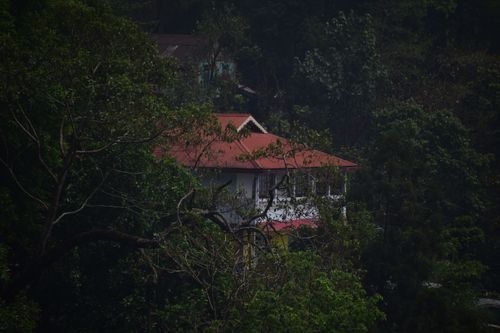 Free A tranquil house with a red roof nestled among dense green forest, offering a serene retreat. Stock Photo