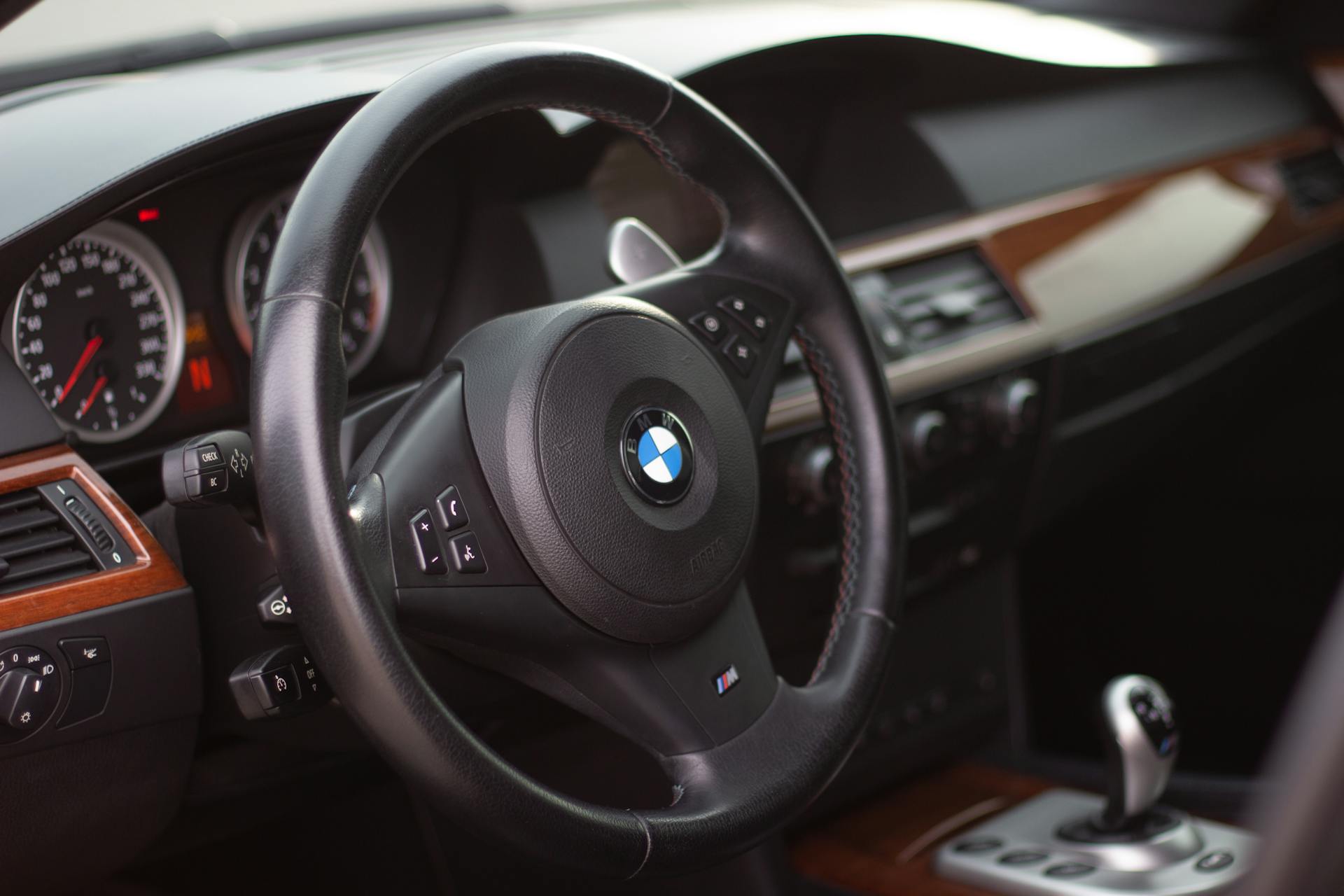 Close-up view of a BMW car interior with focus on the steering wheel and dashboard.