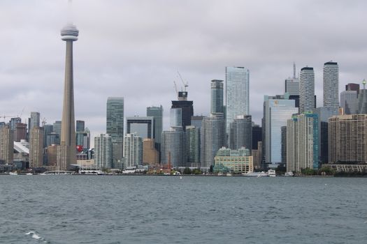 The iconic Toronto skyline featuring the CN Tower, under a cloudy sky, seen from the waterfront.